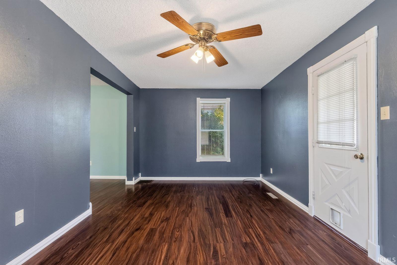 Spacious interior featuring wood-finish flooring, a ceiling fan with light fixture, and a window providing natural illumination