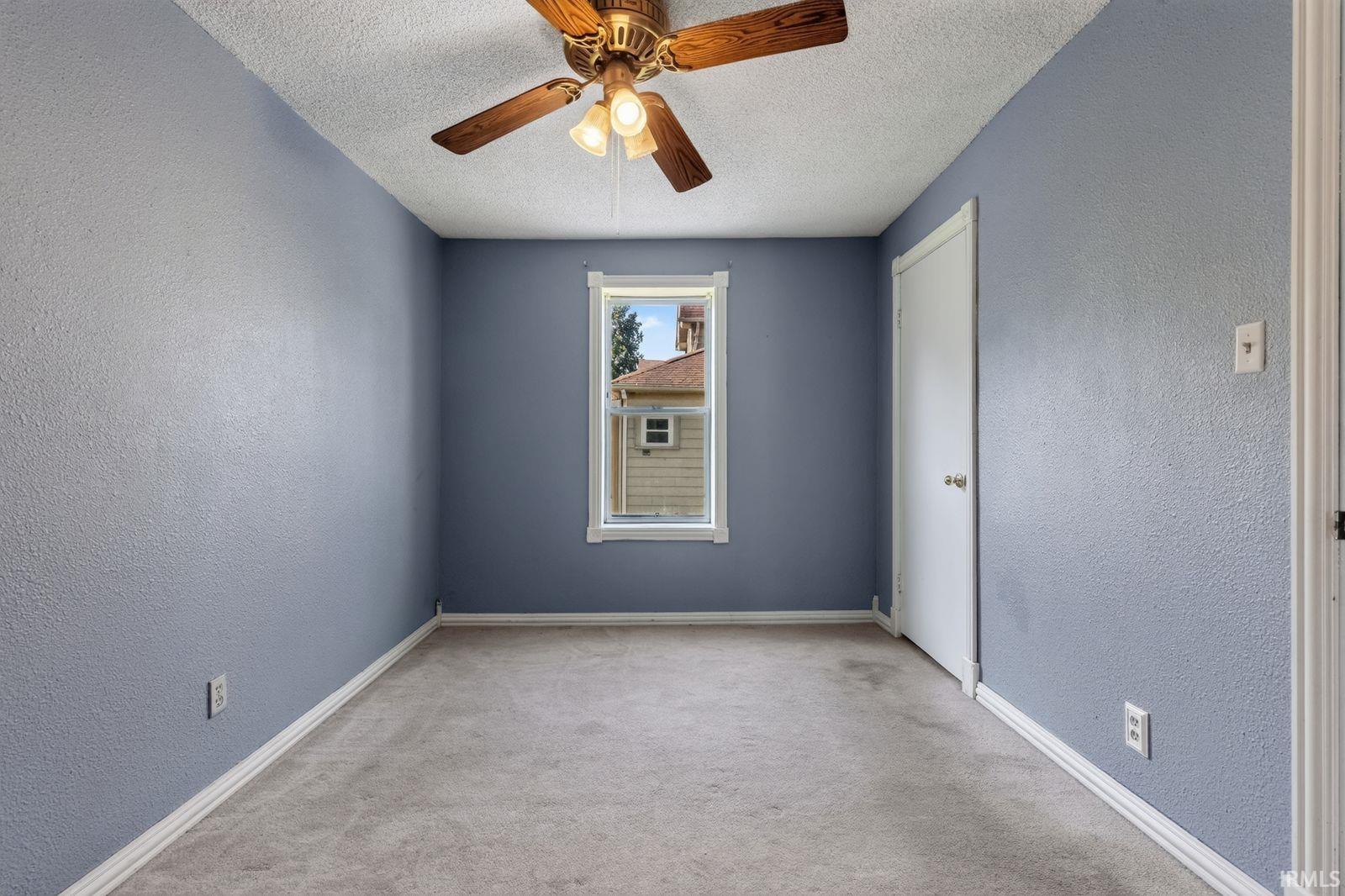 Carpeted room with a ceiling fan, a window, and a white door
