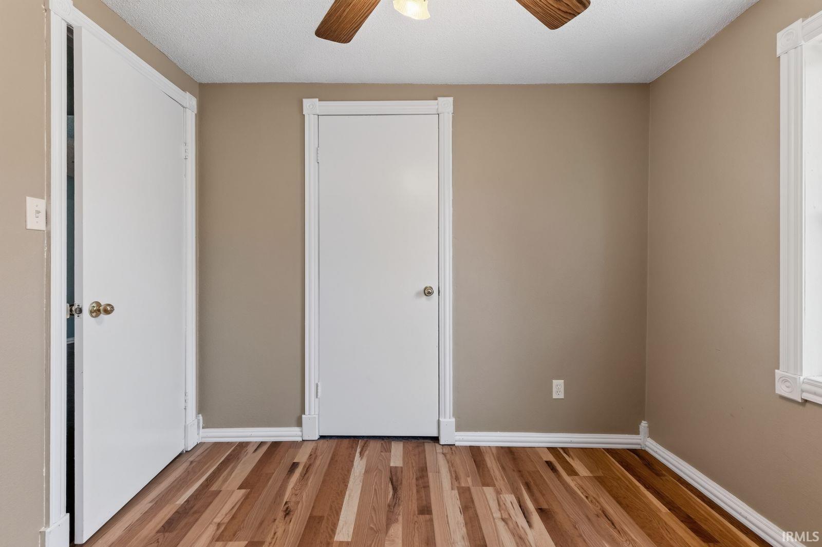 Room featuring wood-finish flooring, neutral wall paint, and white trim