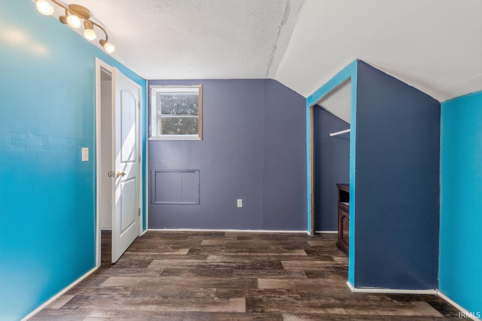 Room with wood-finish flooring, a window, and a built-in closet space