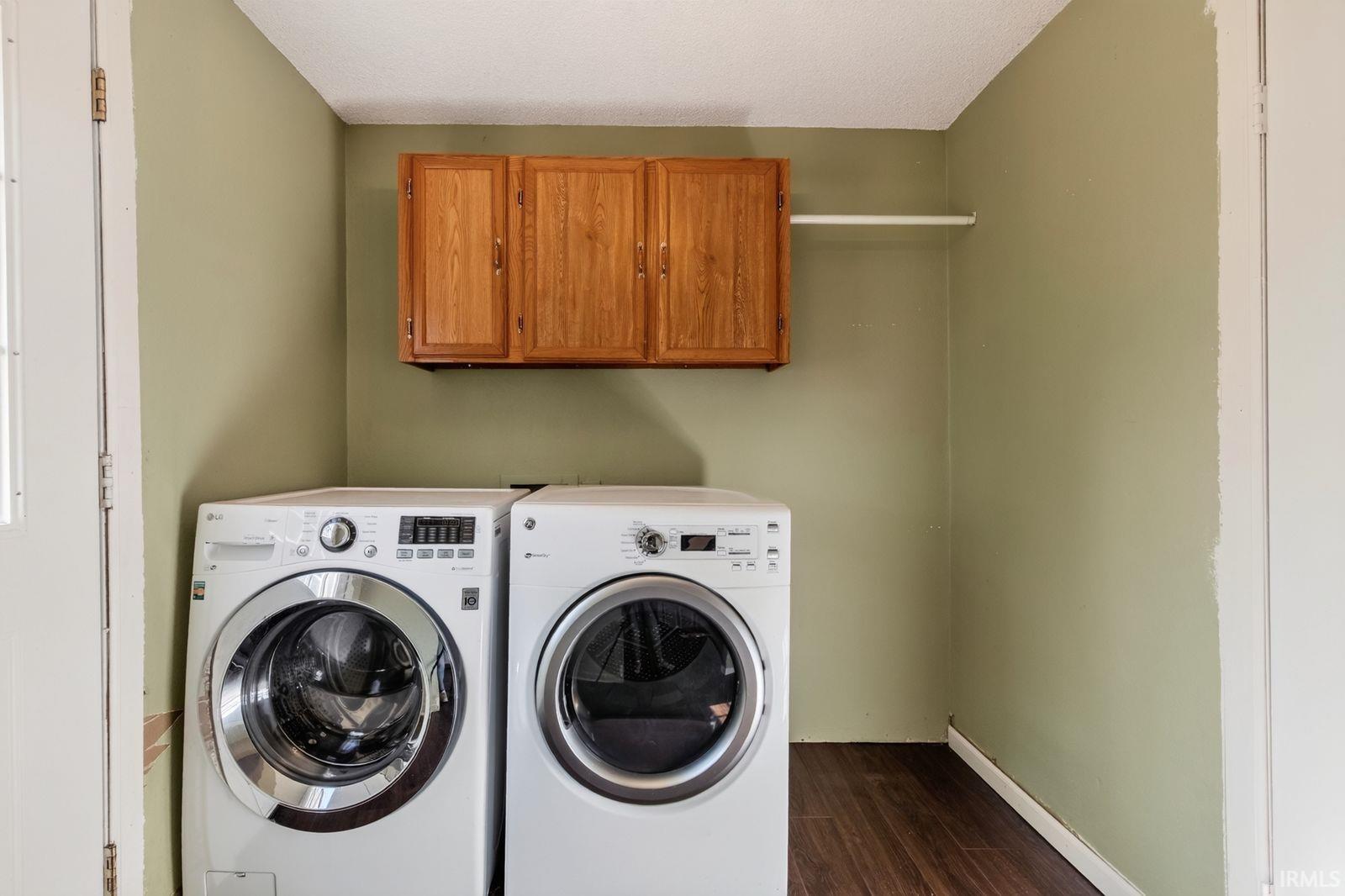 Laundry area featuring wood-finish flooring, overhead cabinetry, and a wall-mounted drying rod