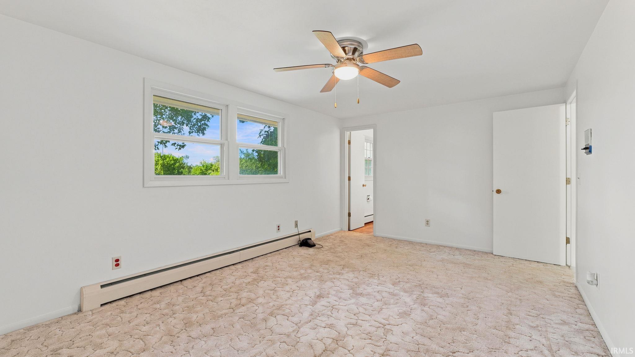 Spacious room featuring white walls, a ceiling fan with light, and two windows