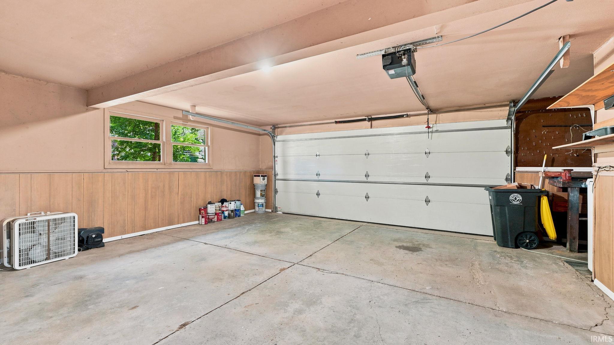 Two-car garage featuring a concrete floor, light-colored walls, and wood-finish wainscoting
