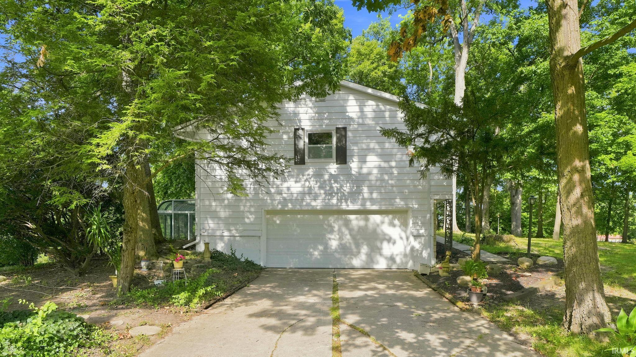 White multi-story exterior featuring a two-car garage and dark window shutters