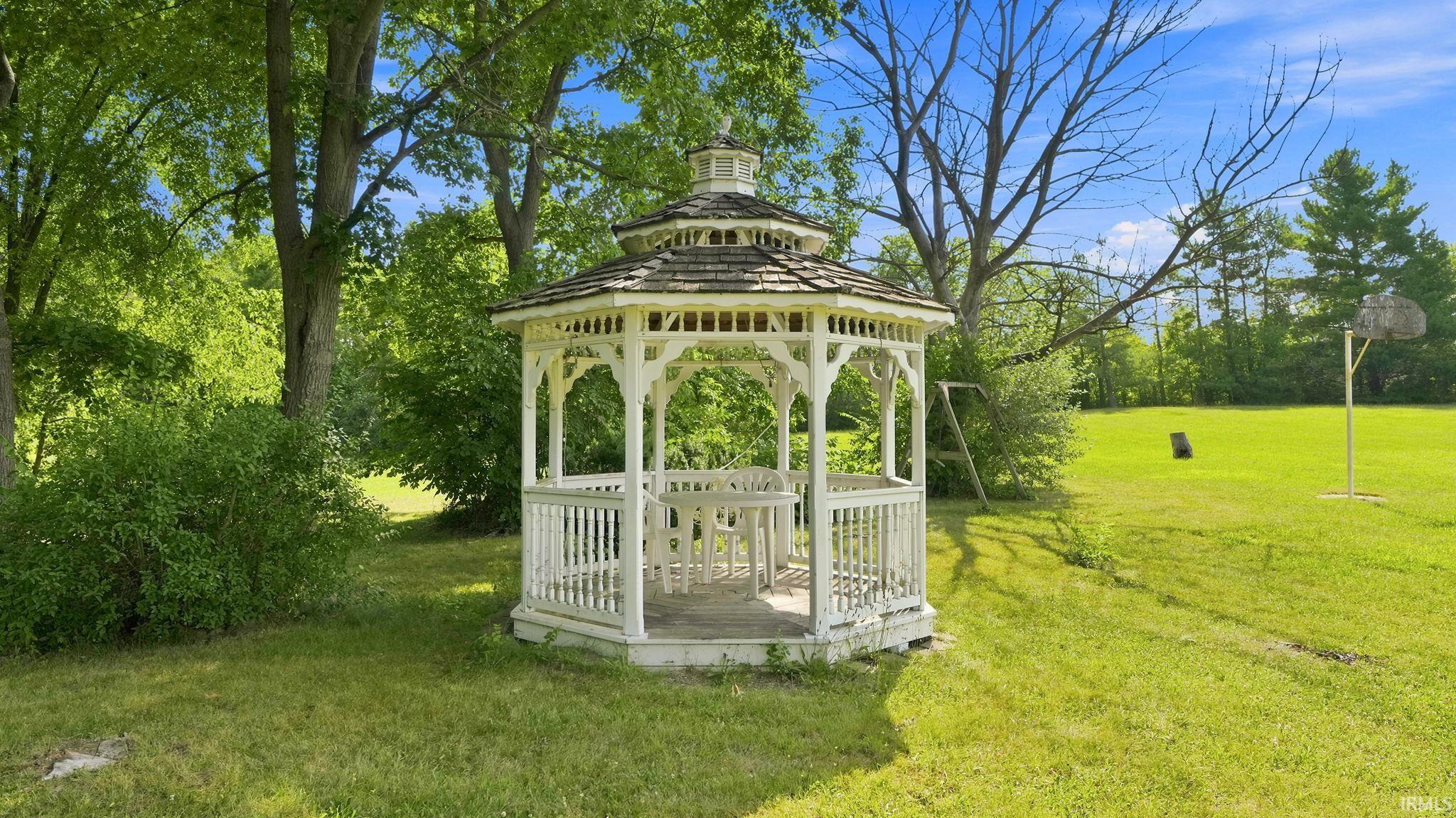 White hexagonal gazebo with a shingled roof