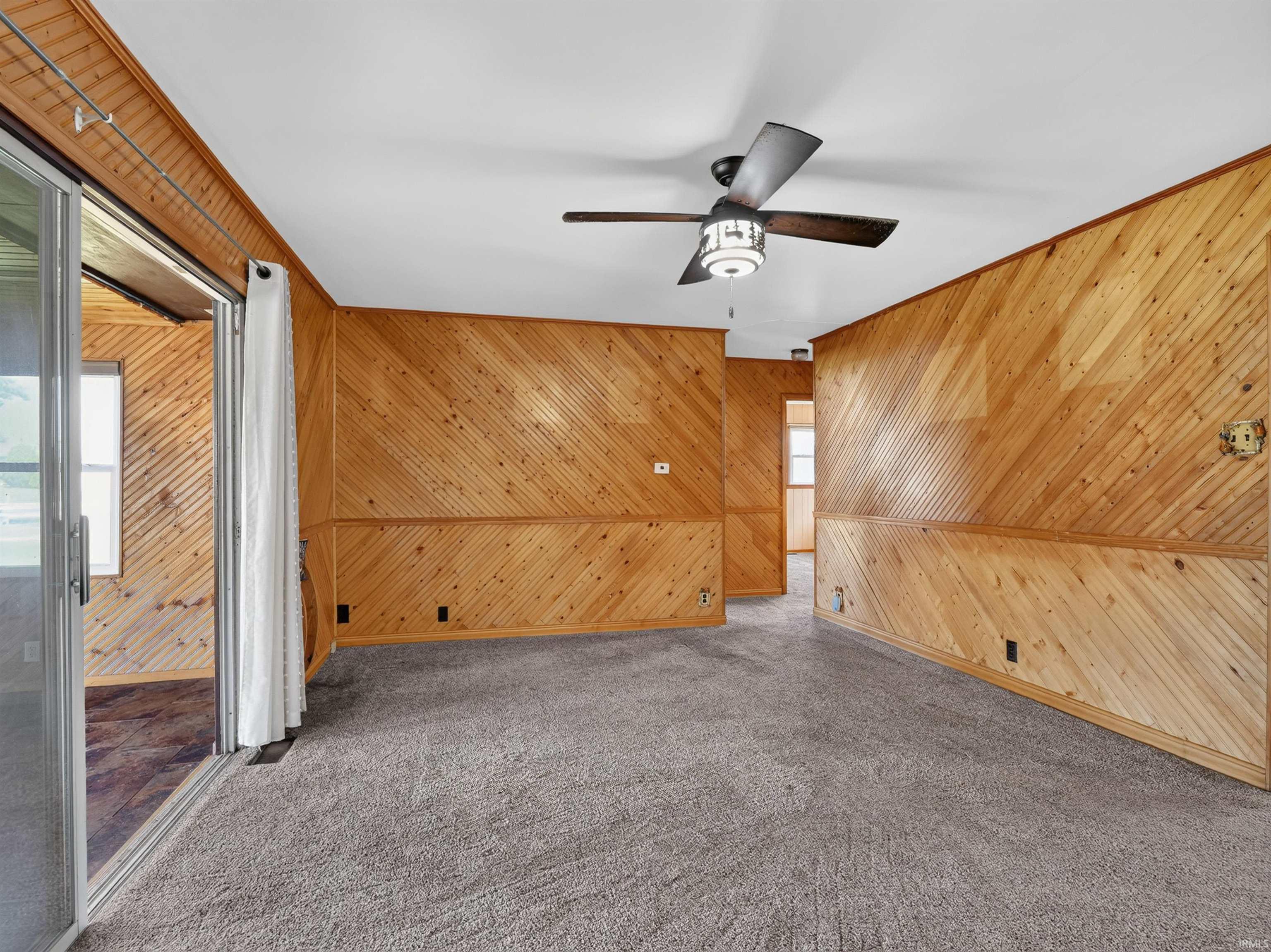 Living area with wood-paneled walls and a ceiling fan