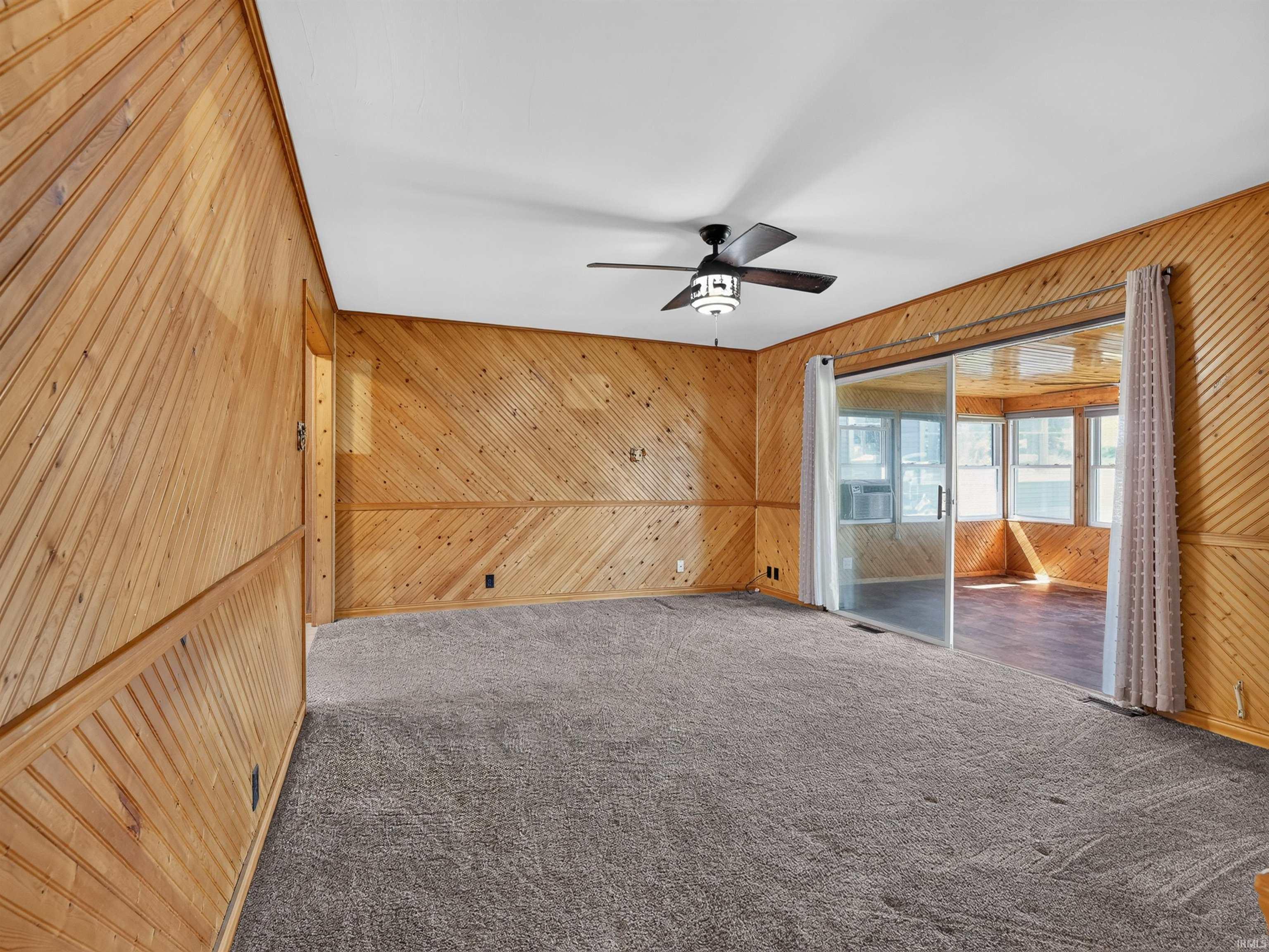 Room featuring diagonal wood paneling and gray carpeting