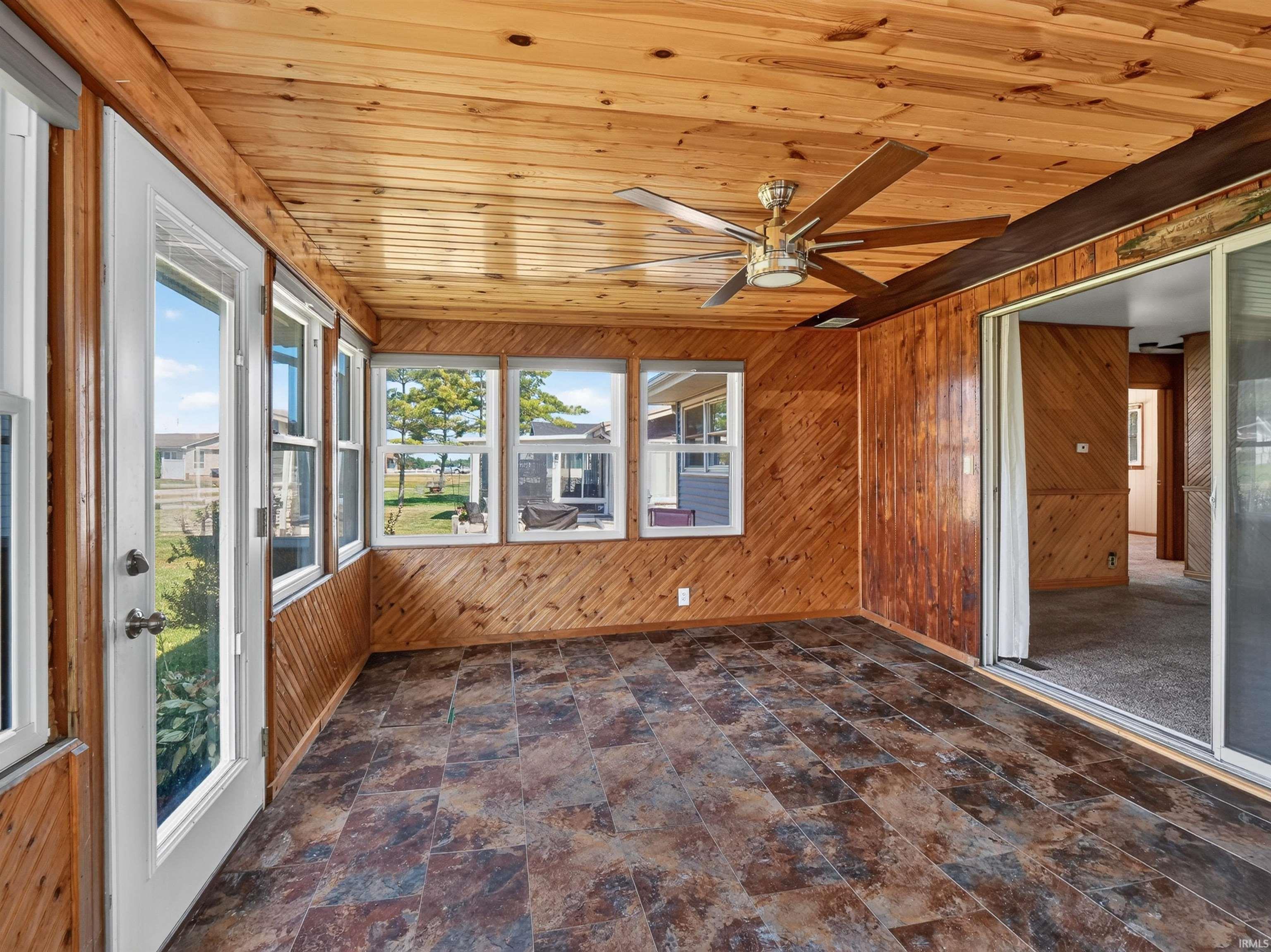 Sunroom featuring extensive wood paneling on walls and ceiling