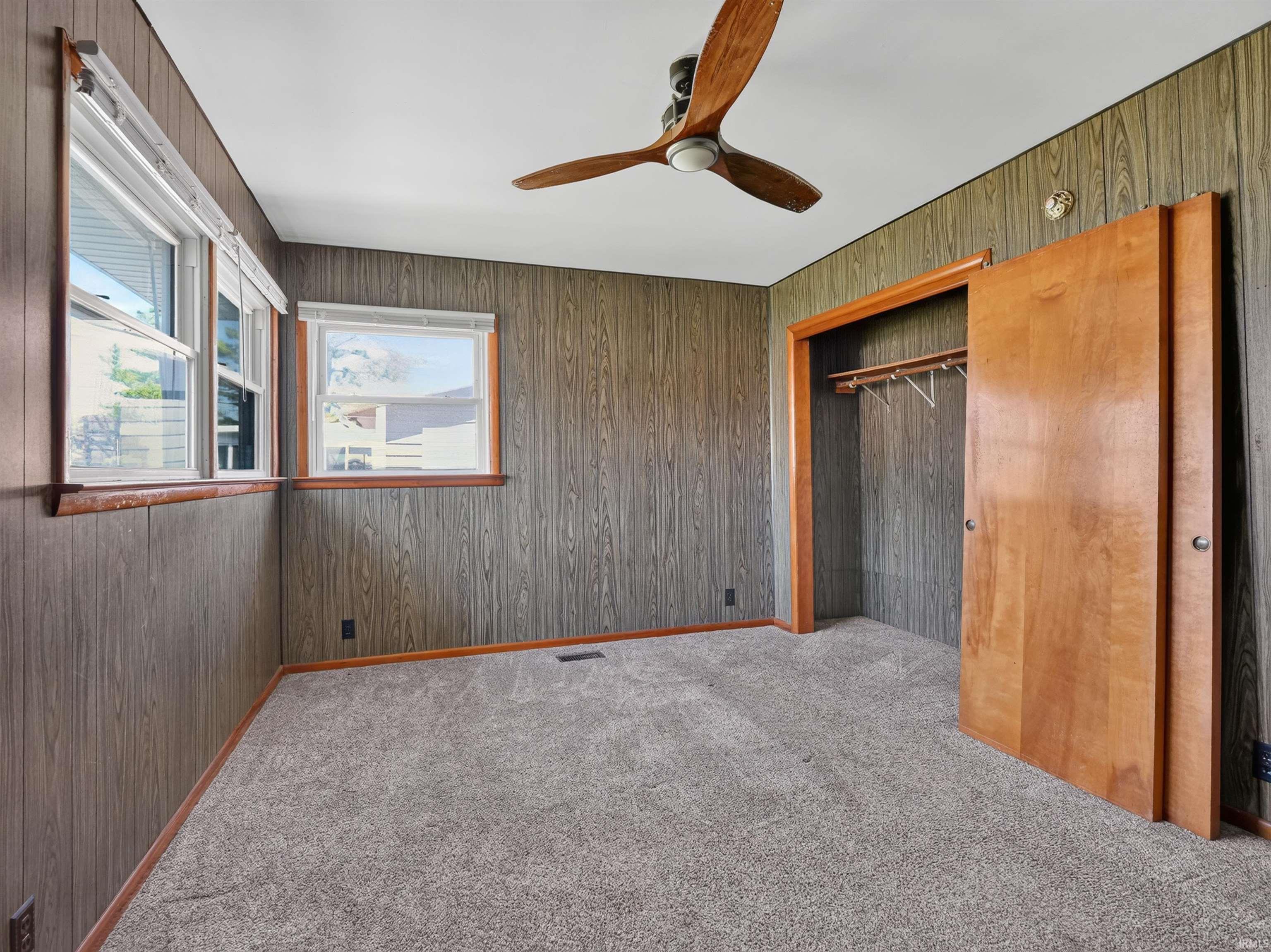 Room featuring wood-look wall paneling and a light gray carpeted floor