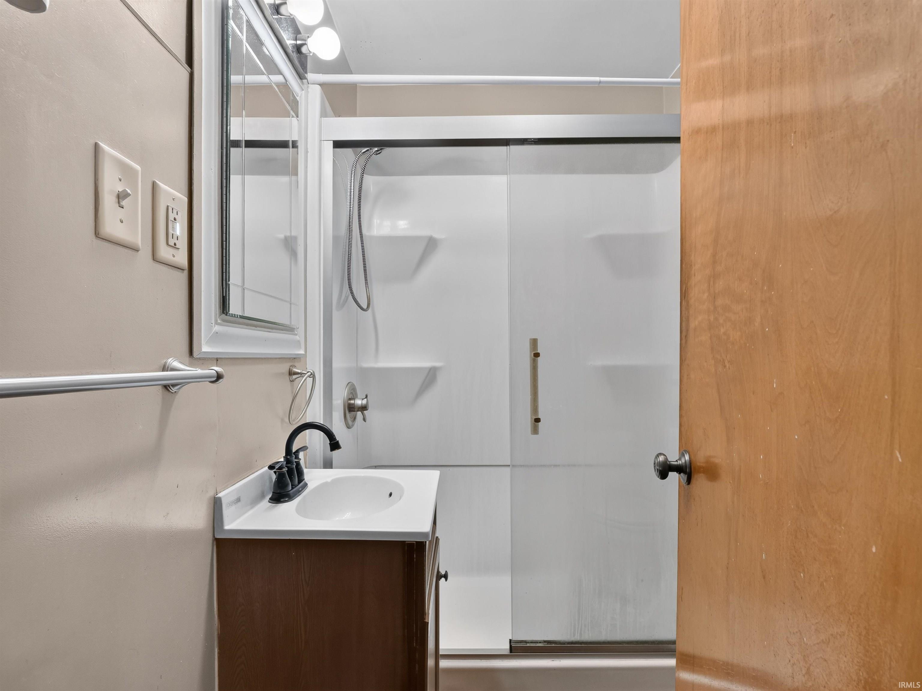 Bathroom featuring a vanity with an integrated sink, a dark-finish faucet, and a shower enclosure with a sliding glass door