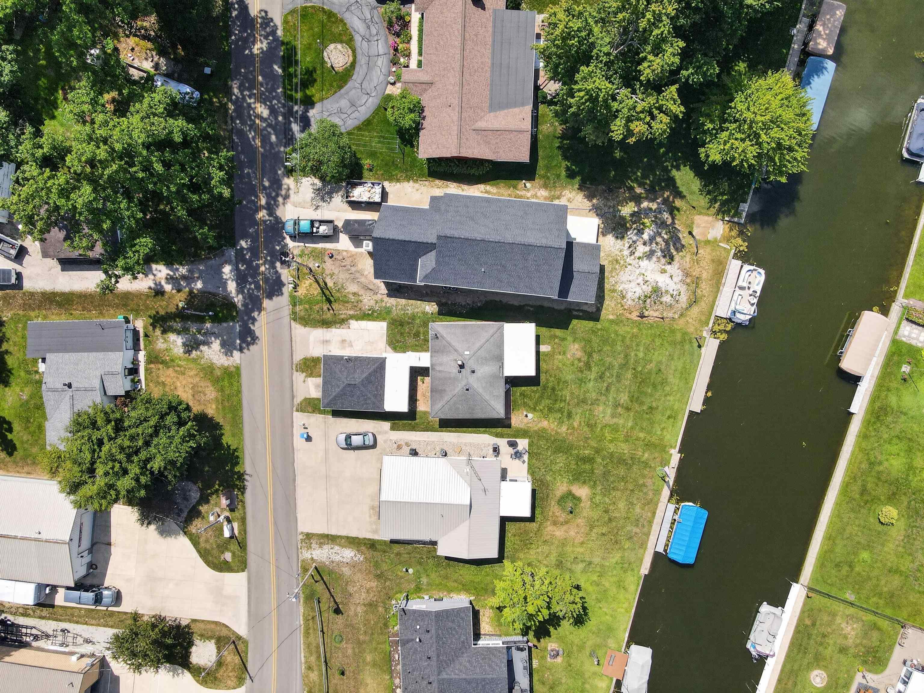 Waterfront property featuring a private boat dock, manicured green lawn, and mature trees