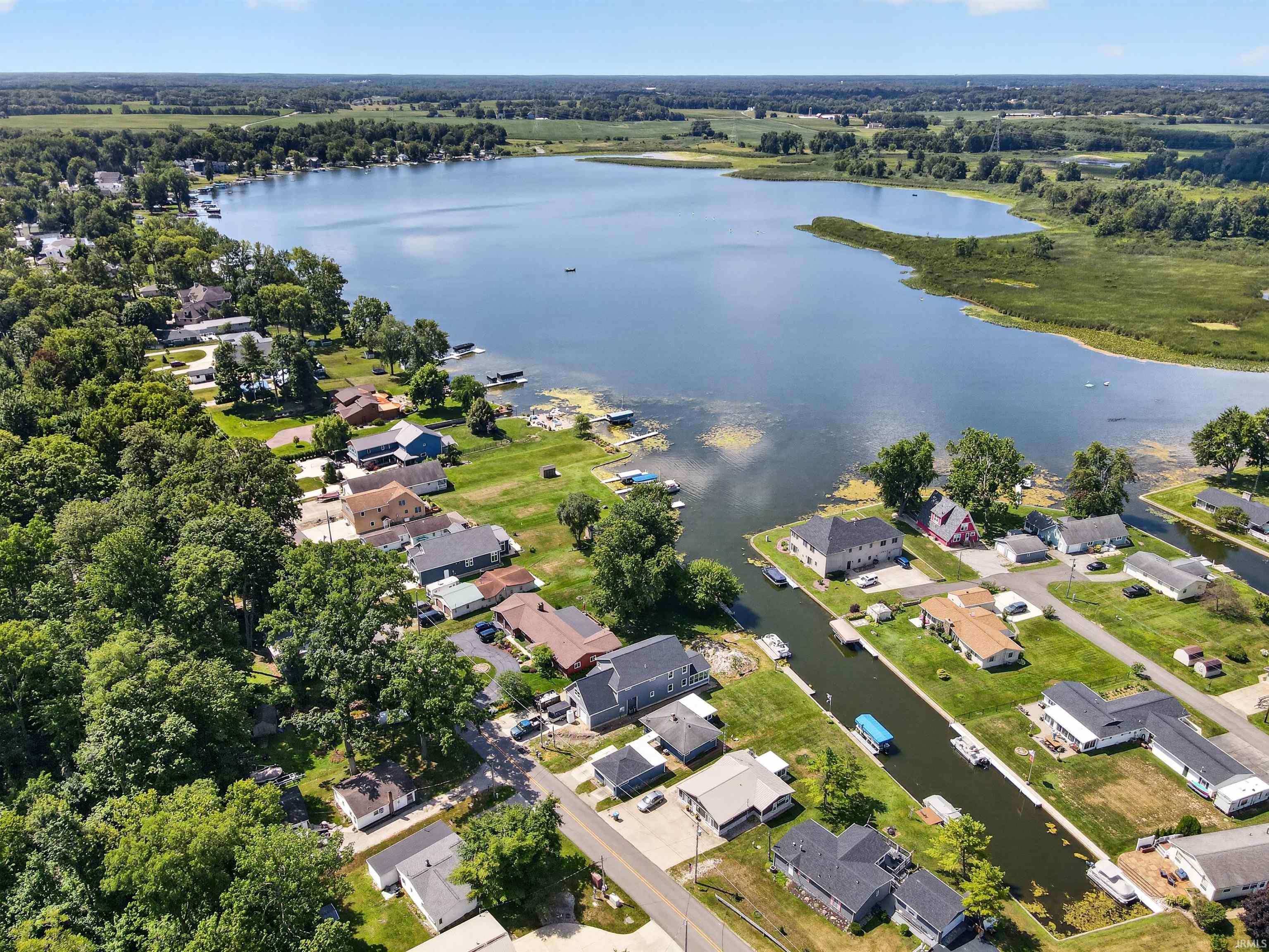 Expansive lake with surrounding properties, mature trees, and waterways featuring boat access