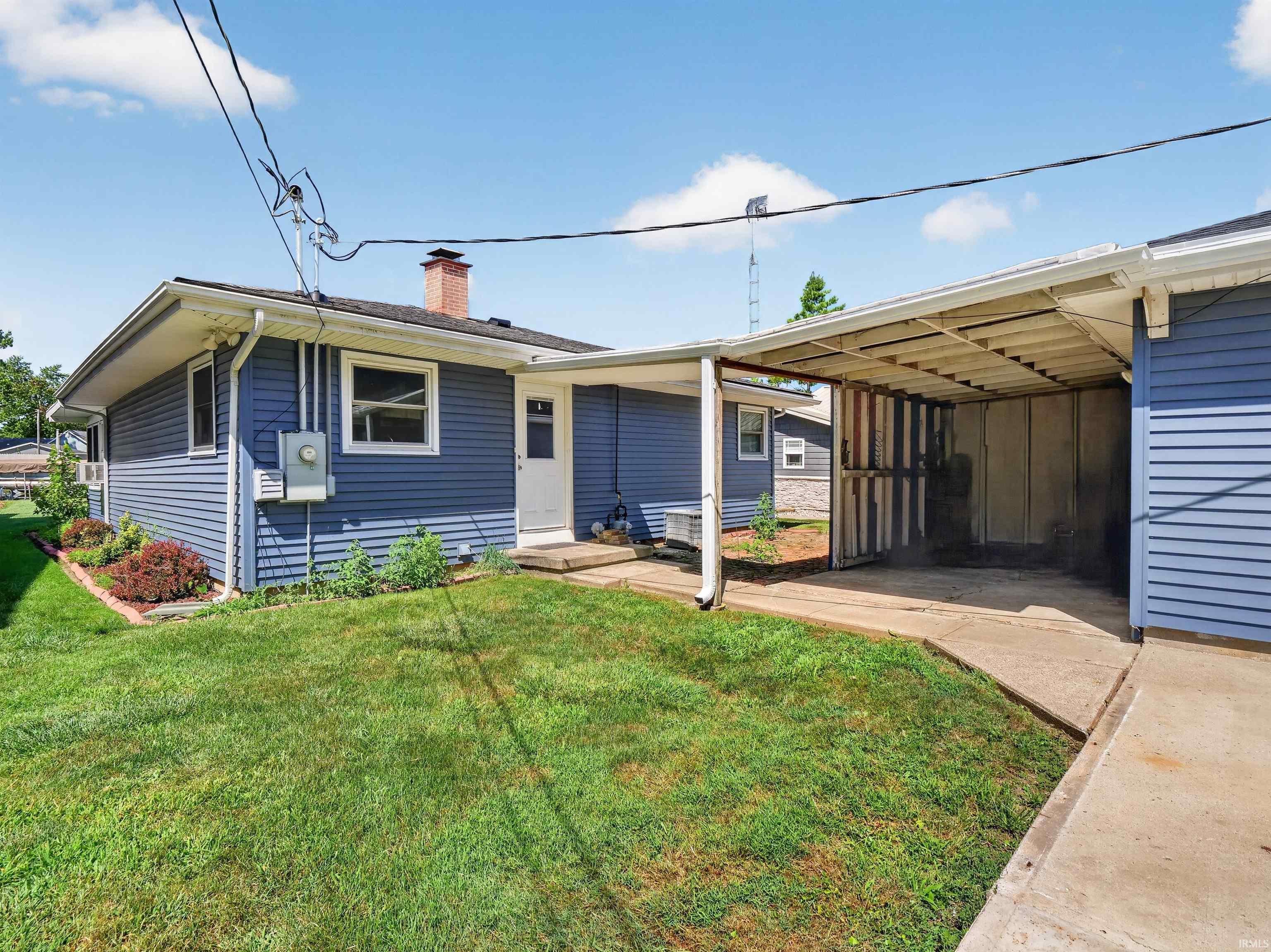 Blue siding exterior with a carport and concrete driveway