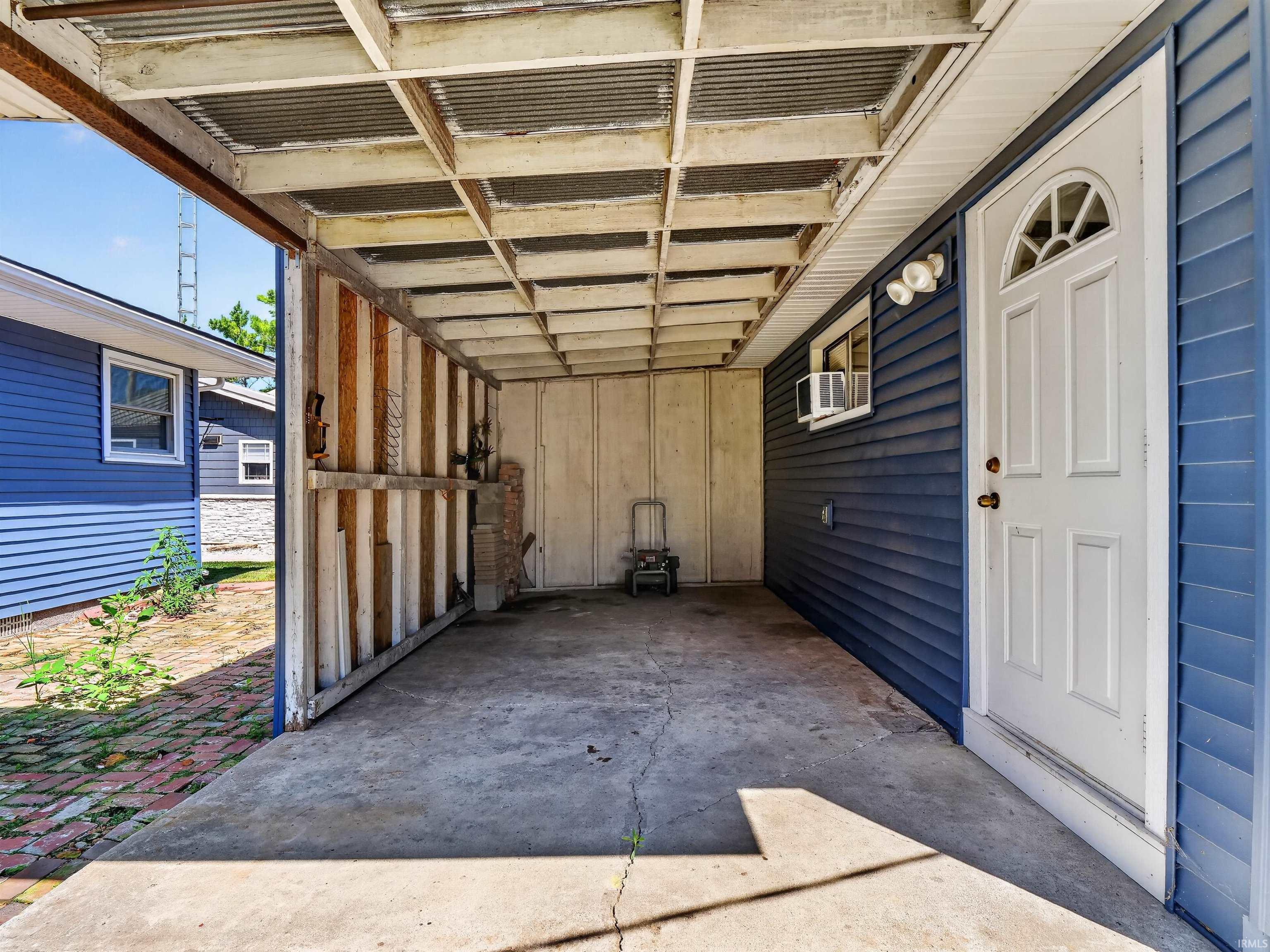 Covered carport with concrete flooring and a corrugated metal ceiling