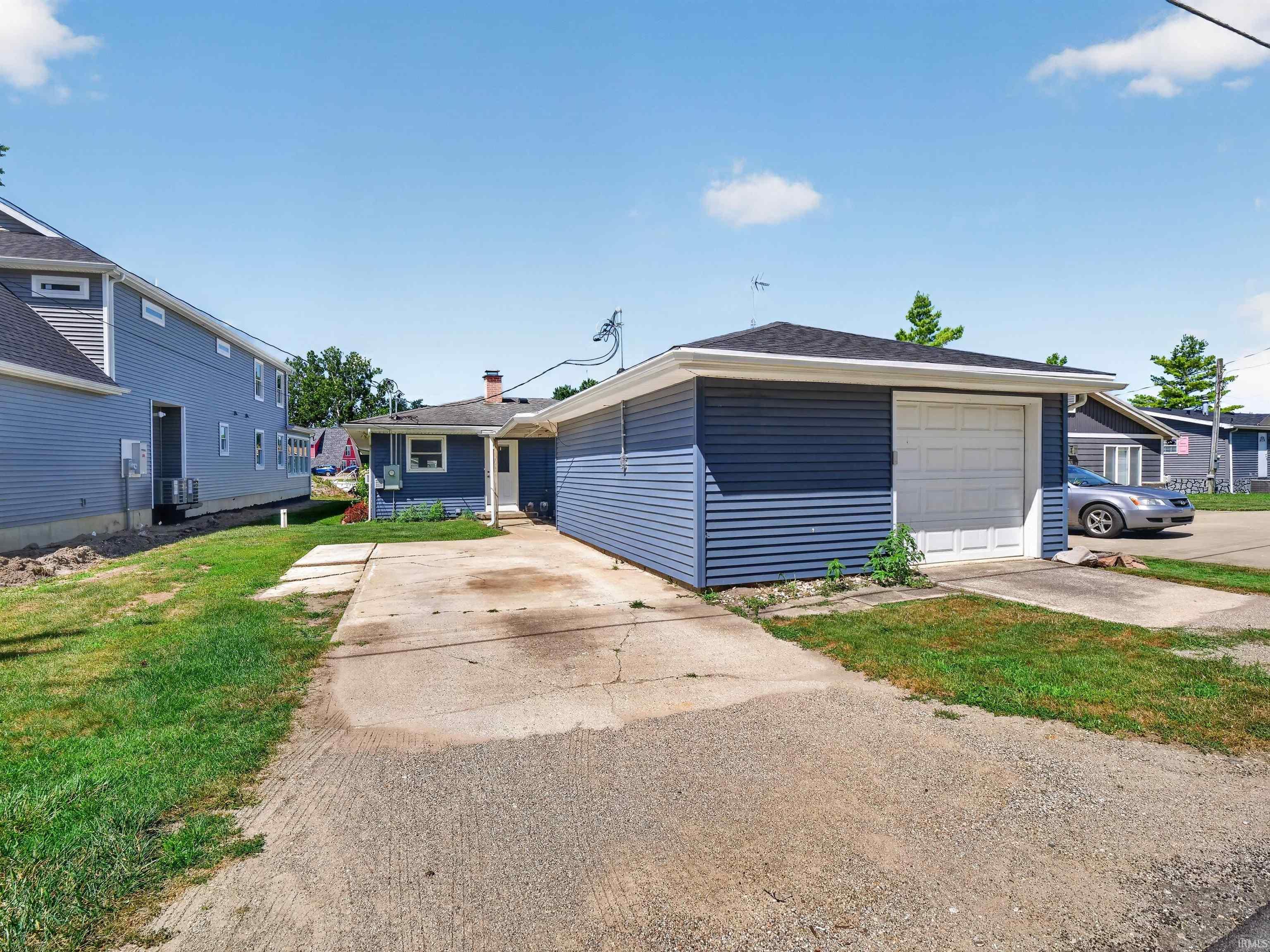 Detached garage with a paneled overhead door, dark blue siding, and white trim