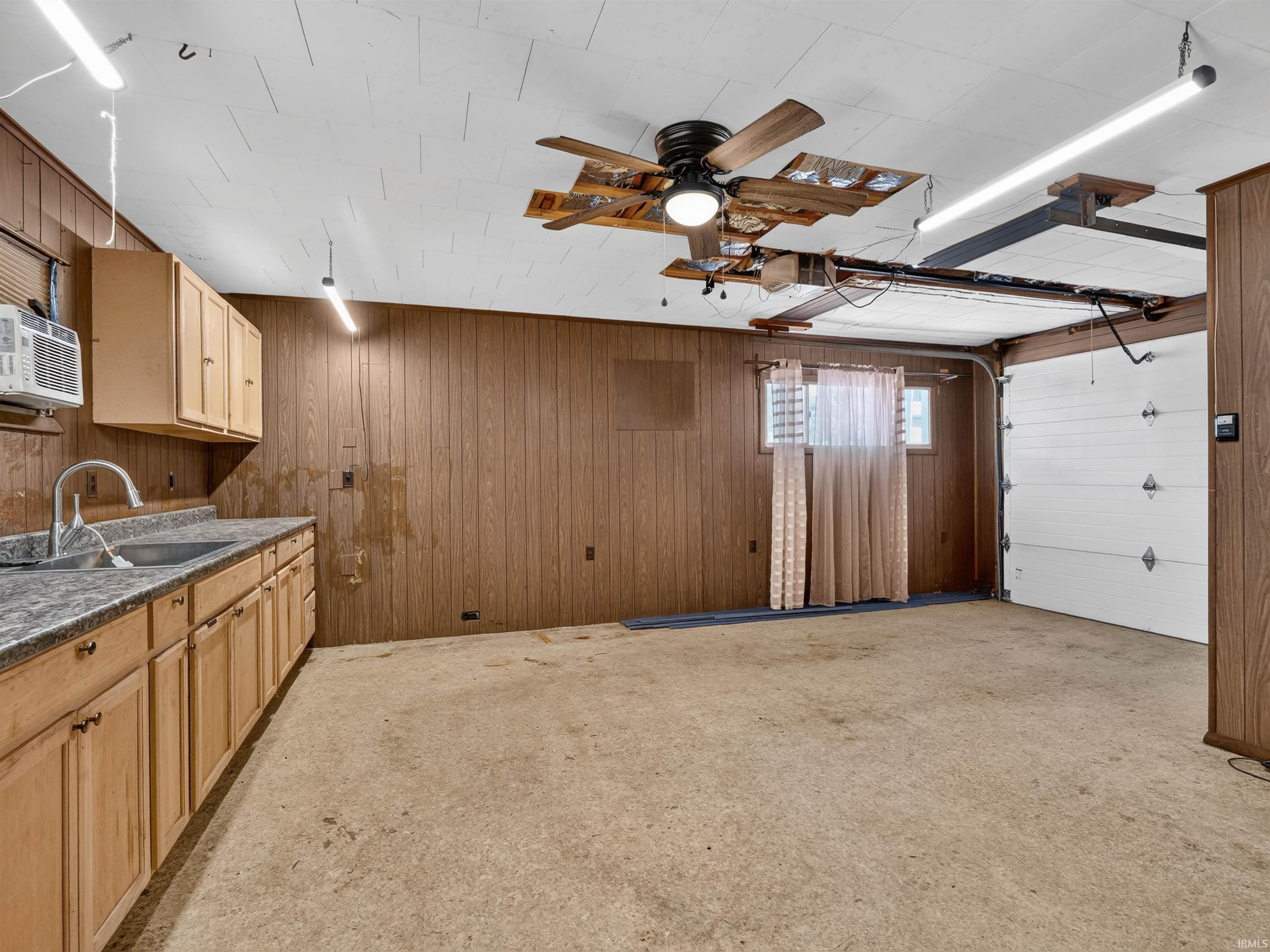 Utility space featuring a built-in countertop with sink, wood-finish cabinetry, and vertical wood-panel walls