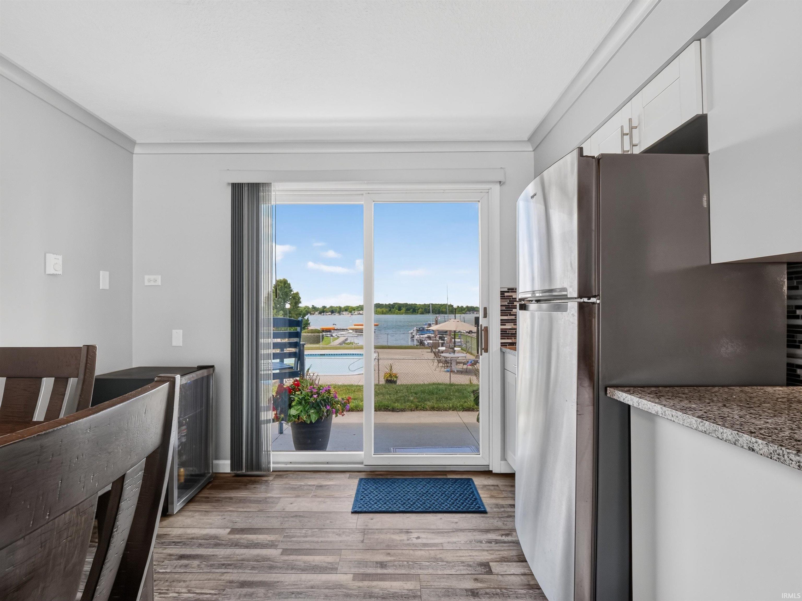 Kitchen area with wood-finish flooring and direct access to an outdoor patio featuring a swimming pool and water frontage