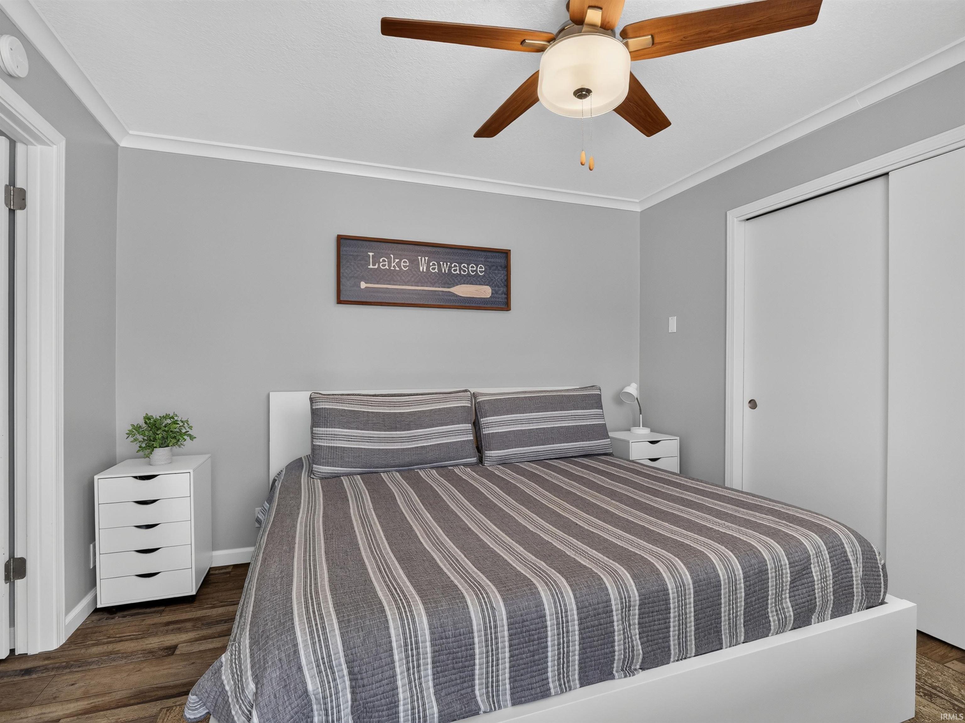 Bedroom featuring wood-finish flooring, light gray wall paint, and white trim