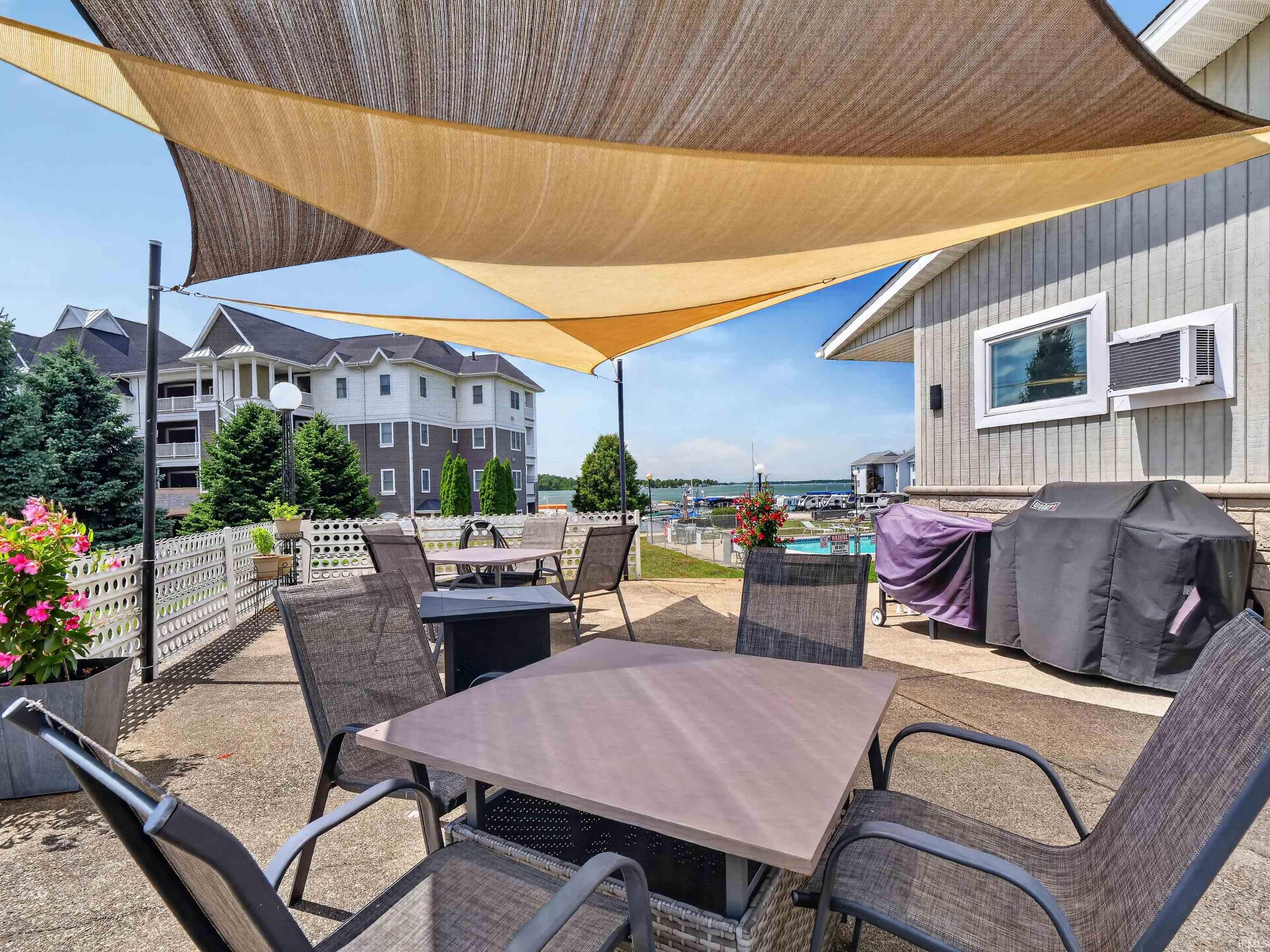 Outdoor patio featuring multiple shade sails, concrete paving, and a decorative white lattice fence