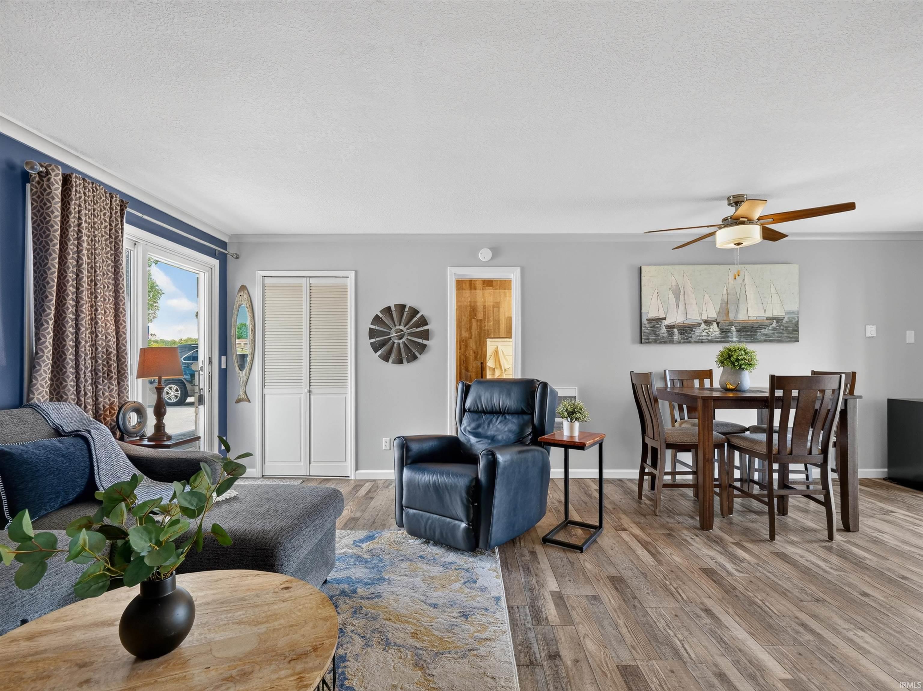 Open concept living area featuring wood-finish flooring, a ceiling fan, and a built-in closet with louvered bi-fold doors