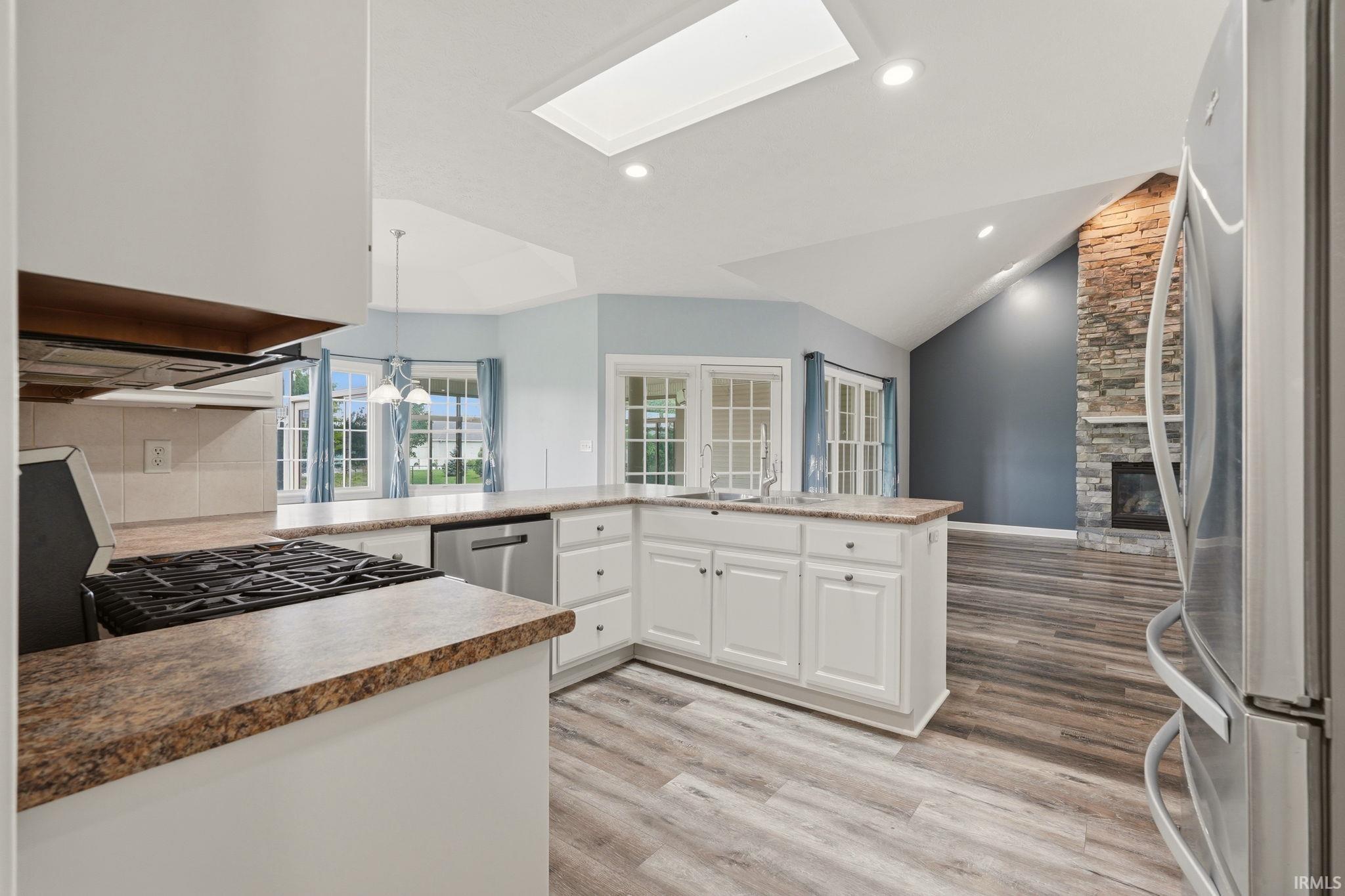 Open-concept kitchen featuring white cabinetry, stone-finish countertops, and stainless steel appliances