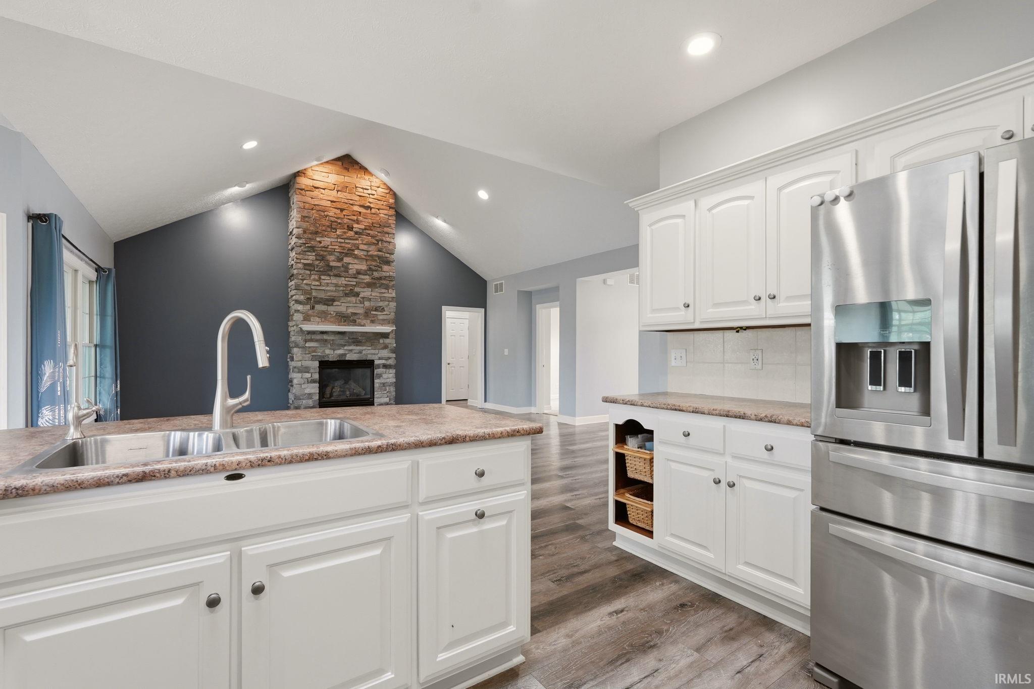 Kitchen with white cabinetry, stainless steel refrigerator, and wood-finish flooring