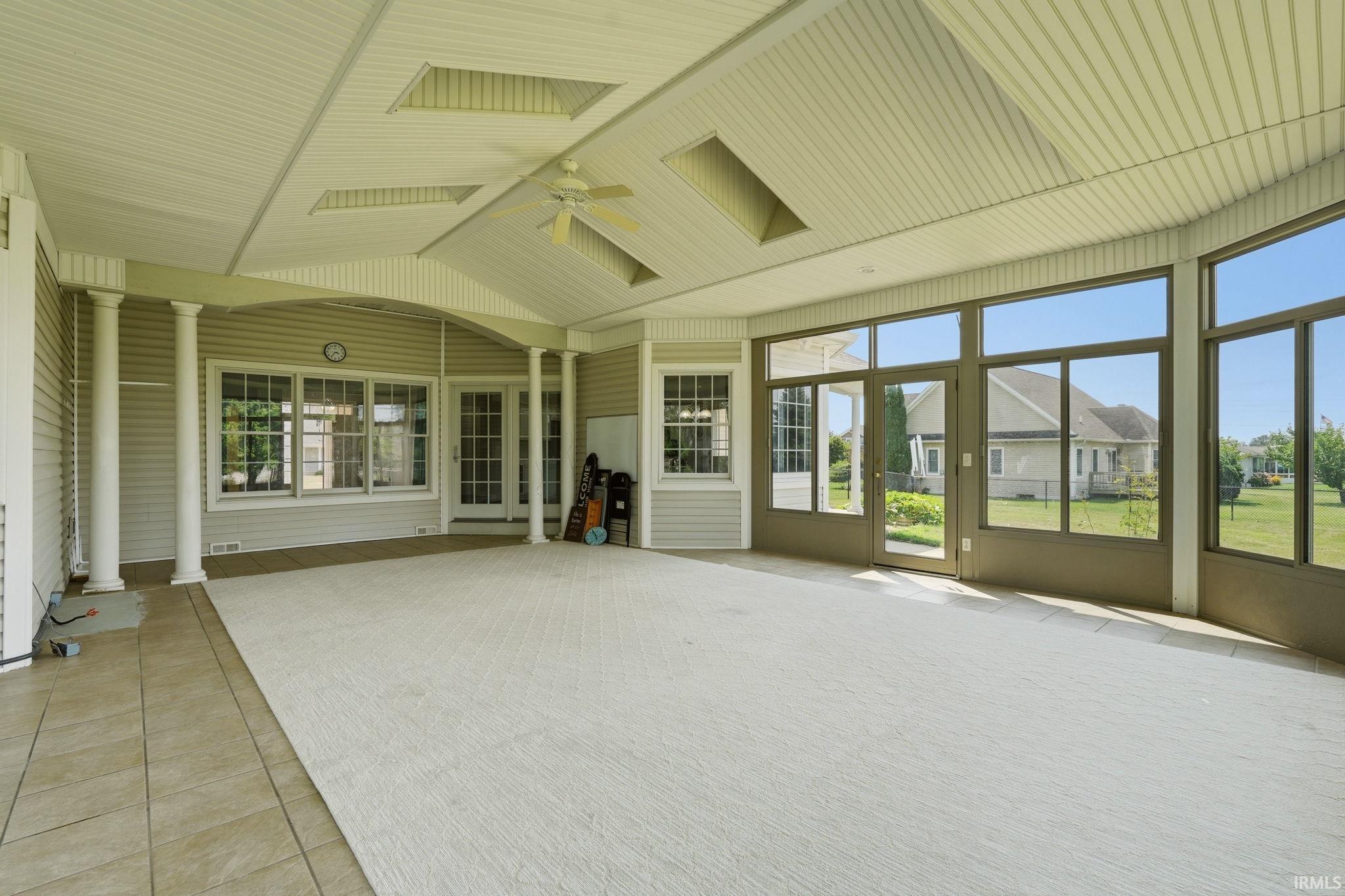 Expansive sunroom featuring floor-to-ceiling windows, a paneled ceiling with recessed lighting, an overhead ceiling fan, and tile flooring