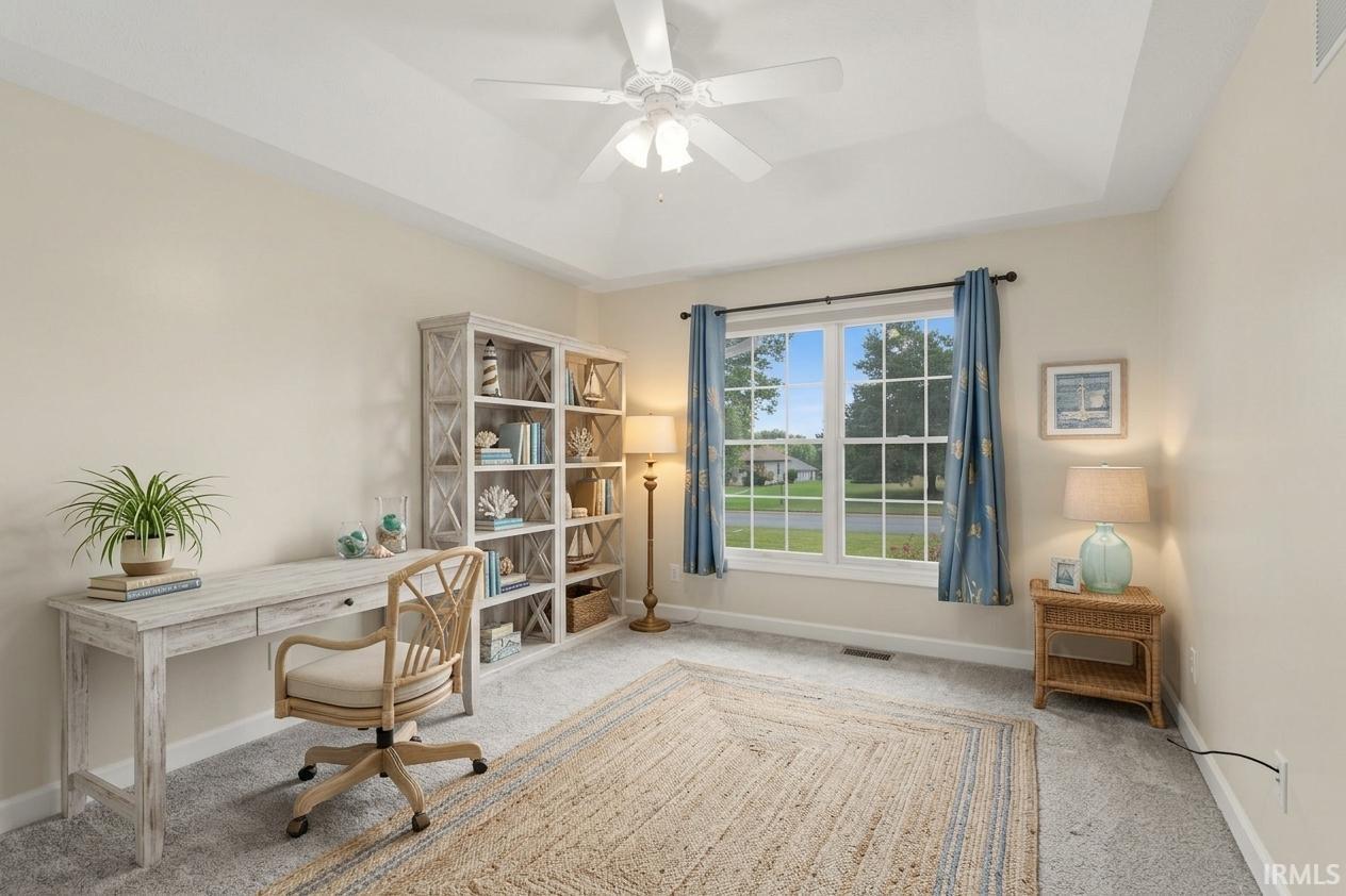 Recessed ceiling with a central fan, large window with natural light, and neutral wall tones