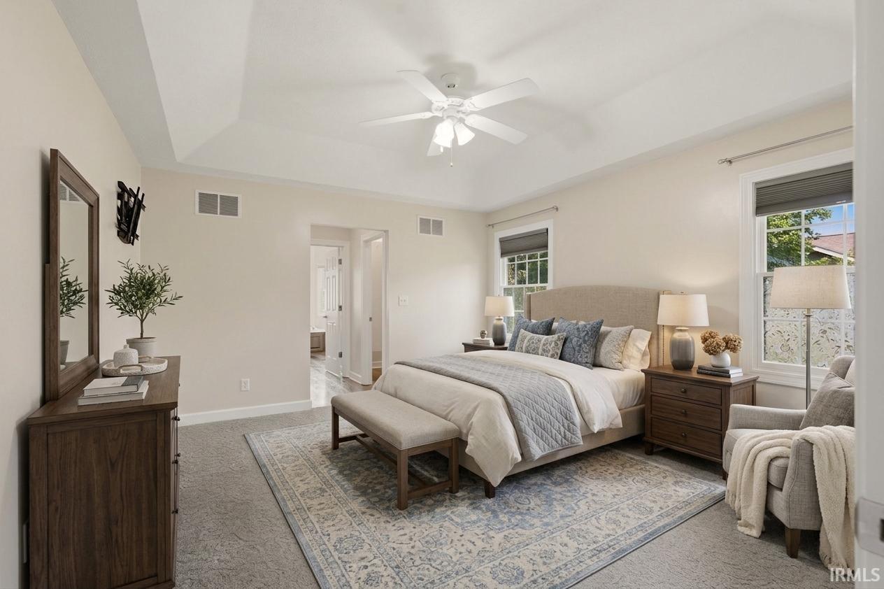 Tray ceiling with a ceiling fan, two windows, and light-toned walls
