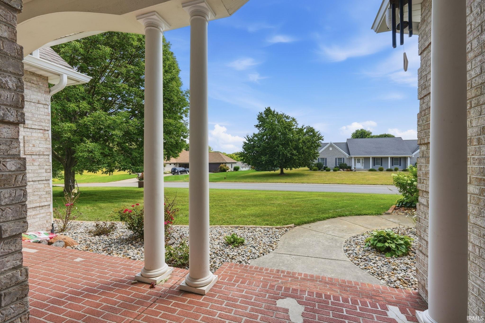 Expansive front porch featuring brick flooring and decorative columns