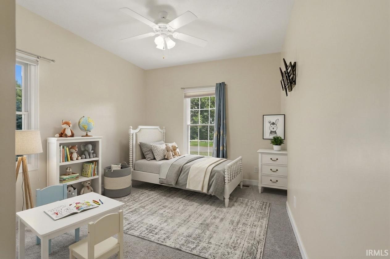 Neutral-toned walls, ceiling fan with integrated lighting, two windows with natural light, wall-mounted television bracket, and light-colored carpeting