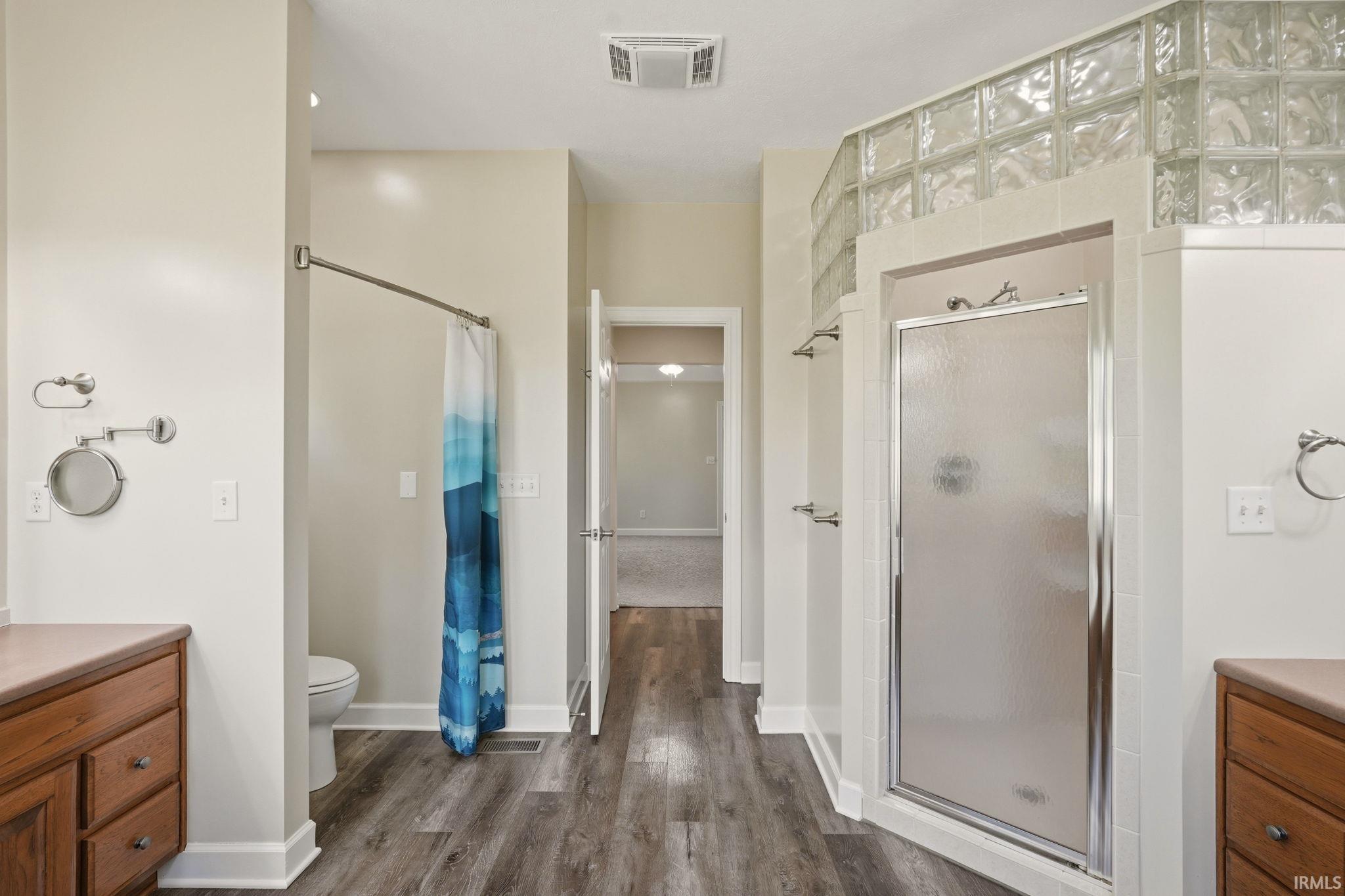 Bathroom featuring a glass block enclosed shower, separate water closet, and wood-finish flooring