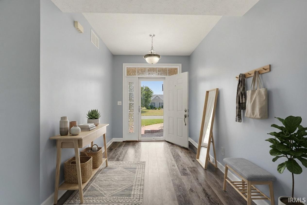 Wood-finish flooring throughout, an entry door with decorative glass panels, and a ceiling-mounted light fixture