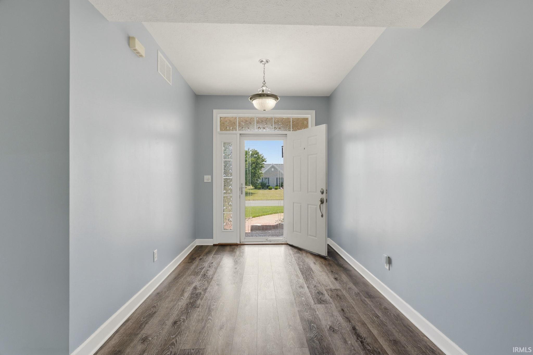 Entryway featuring wood-finish flooring, light blue walls, and white trim