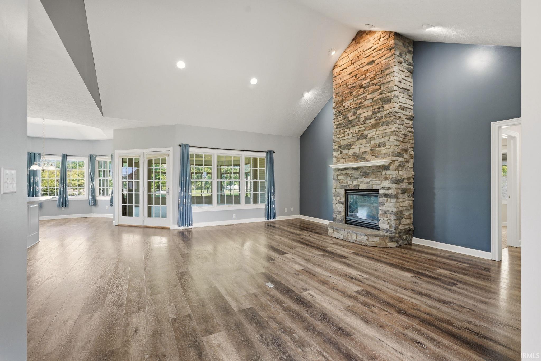Spacious interior featuring wood-finish flooring, a vaulted ceiling, and recessed lighting