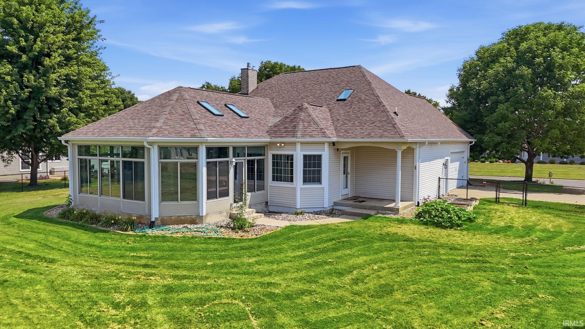 Rear exterior featuring a sunroom addition, covered porch, and skylights