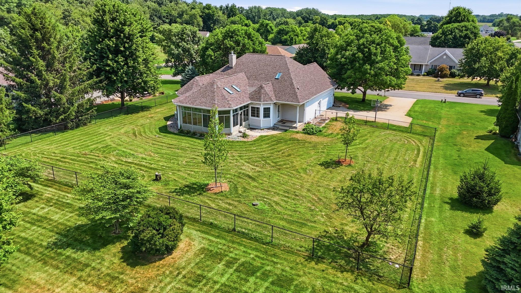 Expansive green lawn surrounds the property, featuring a white exterior and a brown shingle roof