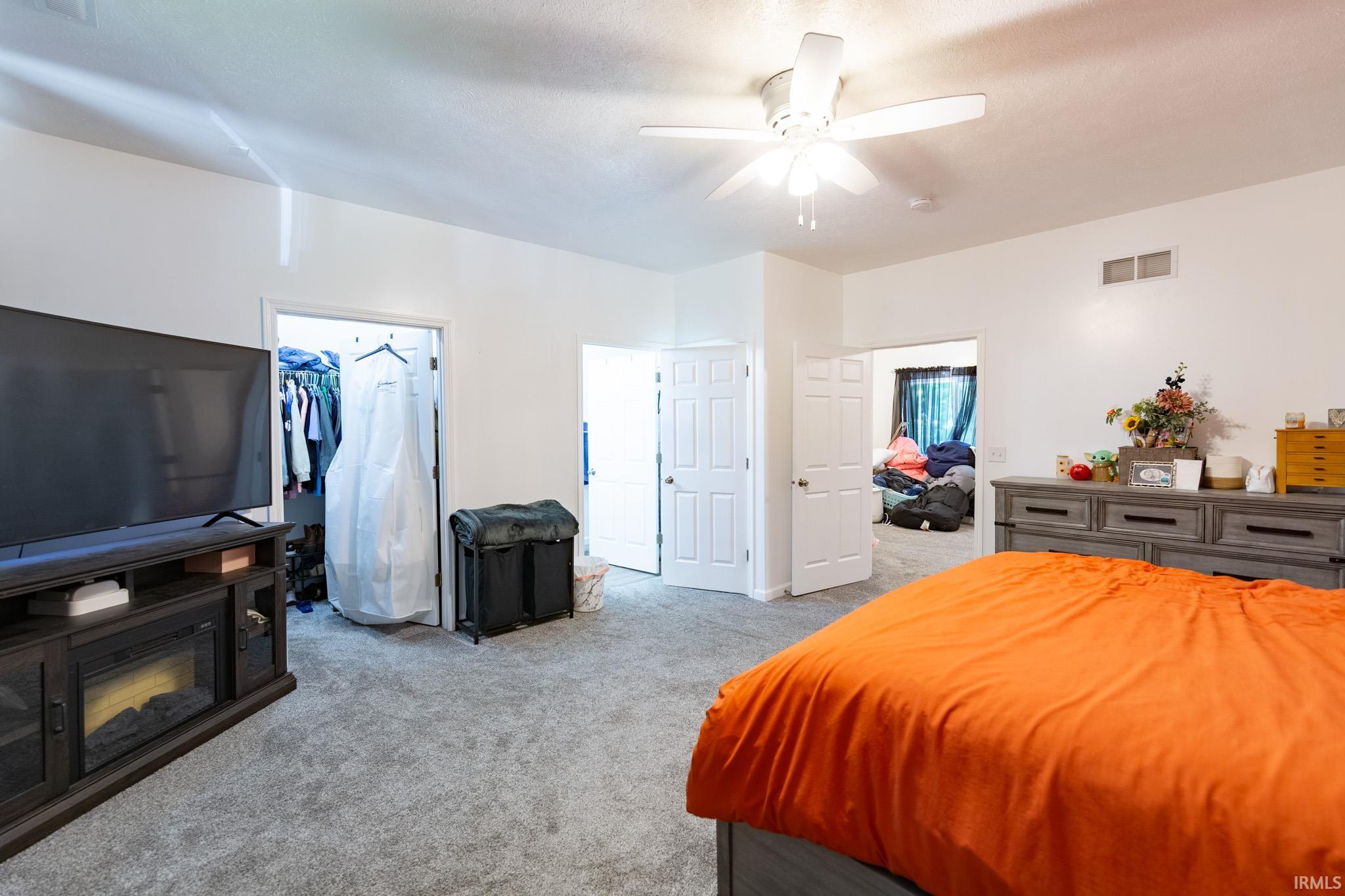 Carpeted room with a ceiling fan, white walls, and a built-in media console with an electric fireplace