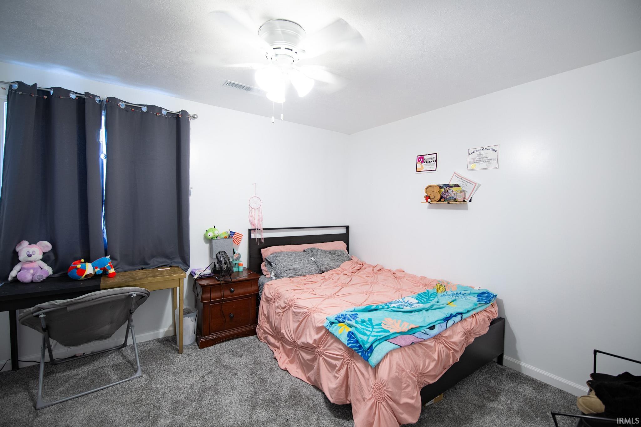 Carpeted room with a ceiling fan light fixture