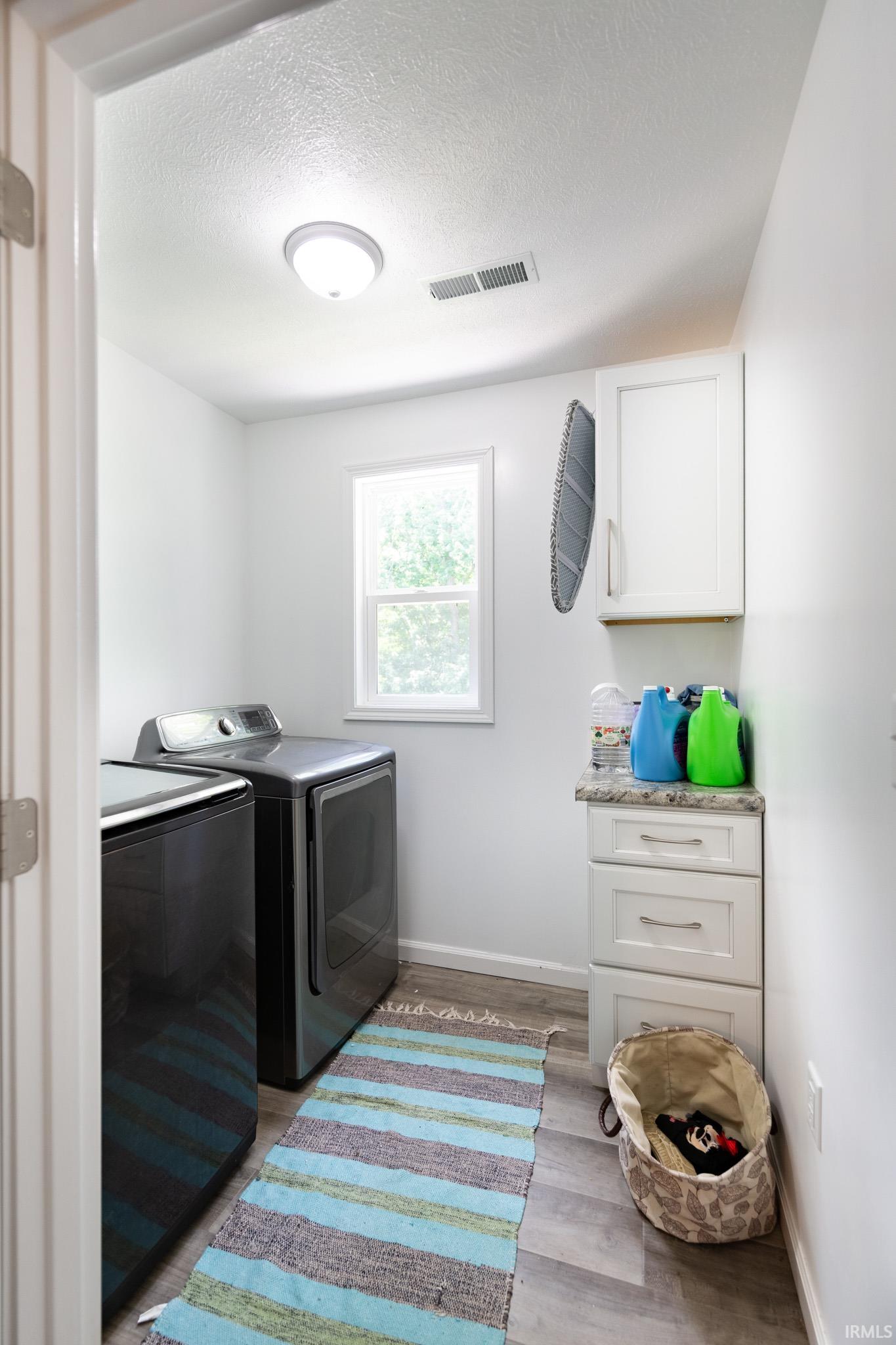Dedicated laundry space featuring wood-finish flooring and a single window