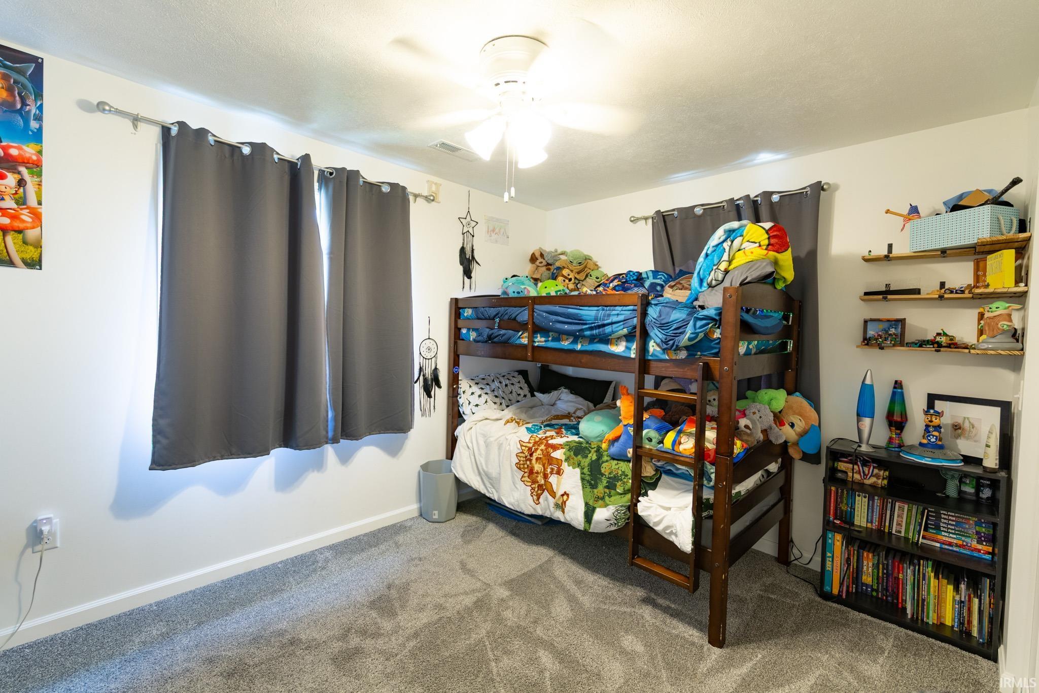 Bedroom featuring light gray carpet flooring, white walls, and a ceiling fan with integrated lighting