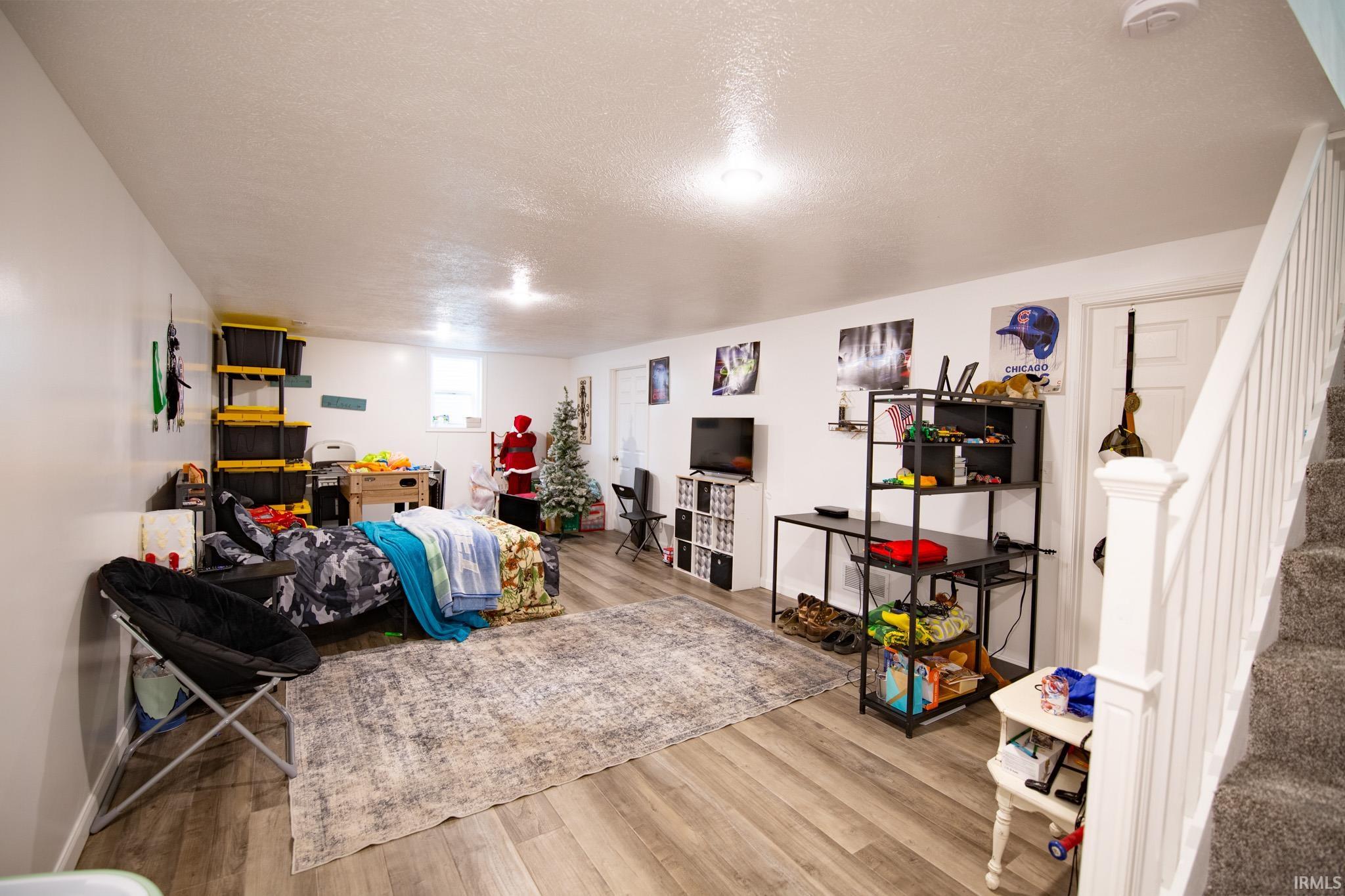 Finished lower-level space featuring wood-finish flooring, recessed lighting, and white walls