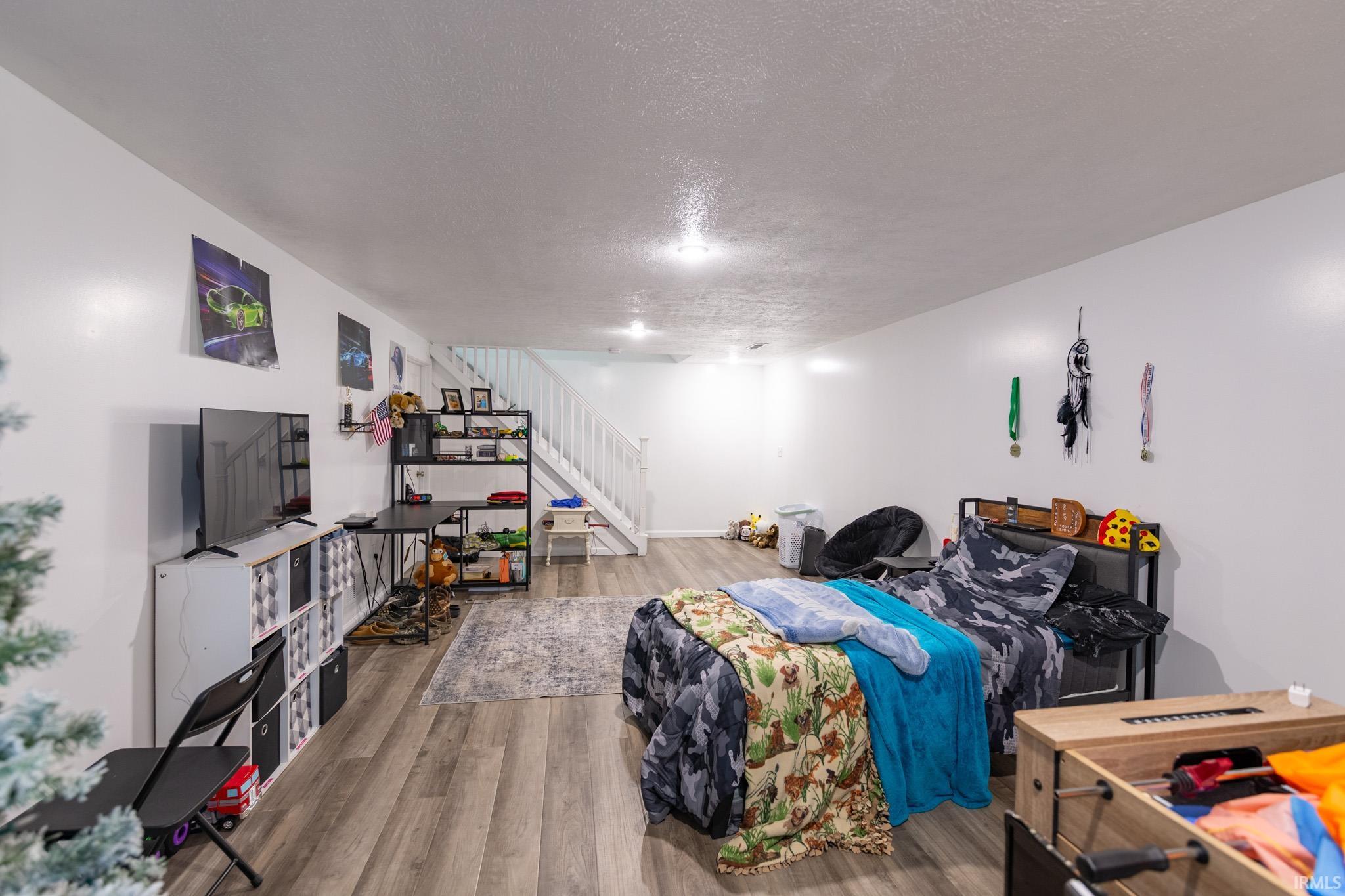 Spacious room featuring wood-finish flooring, white walls, and recessed lighting