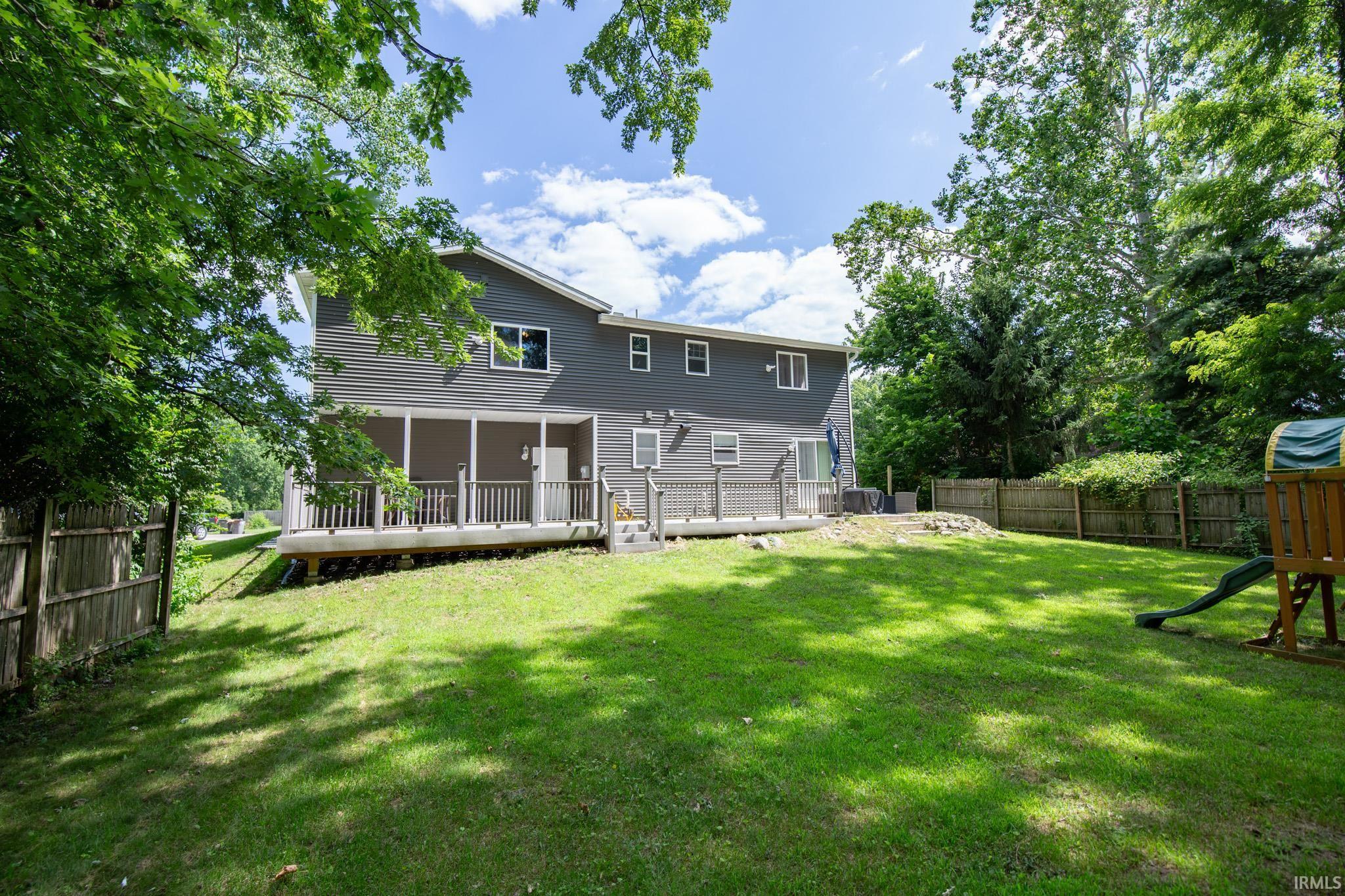 Spacious backyard featuring a manicured lawn, multi-level wood deck, screened porch, and privacy fencing