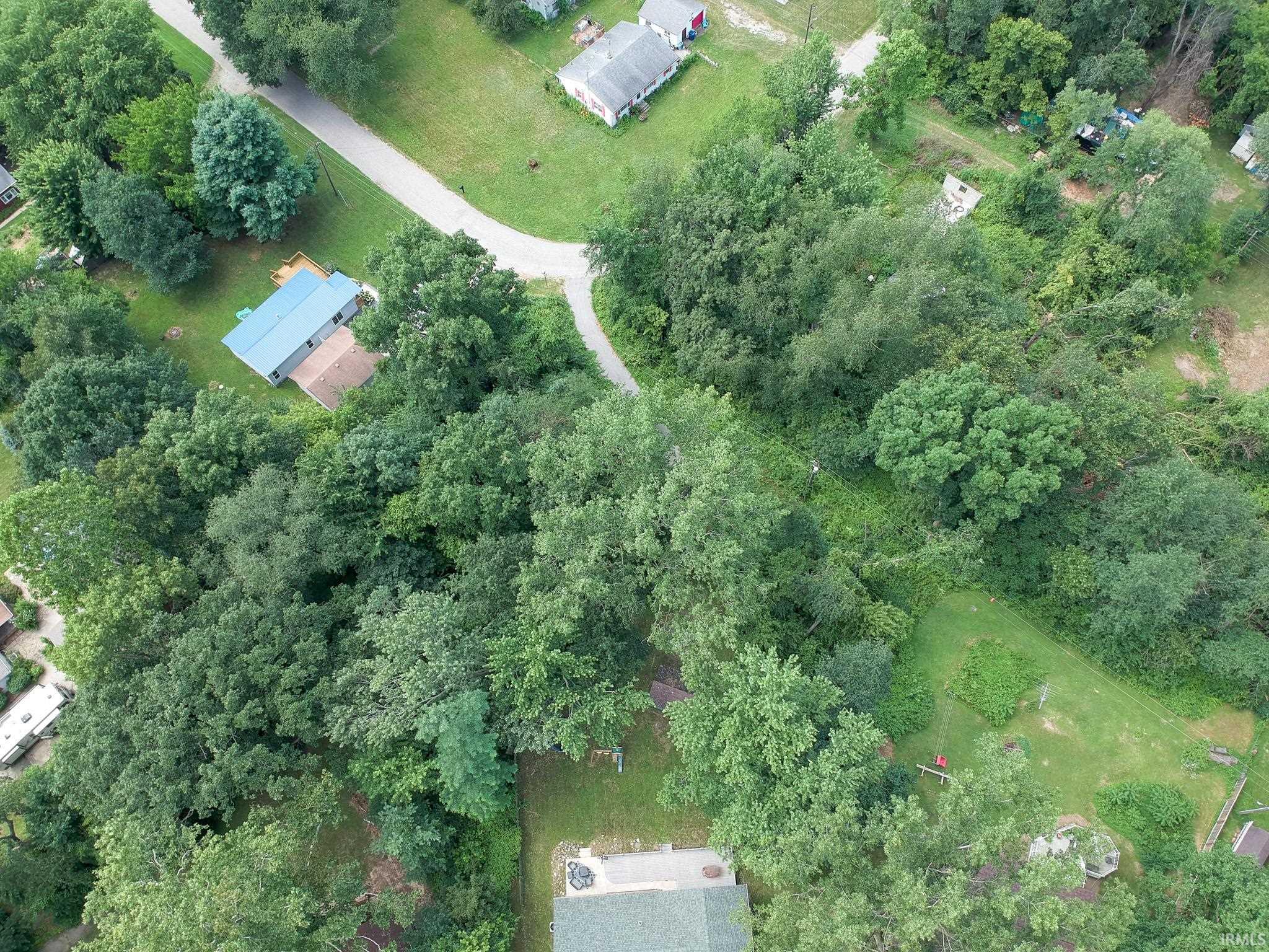 Wooded lot featuring a detached residence with a blue metal roof and an exterior deck