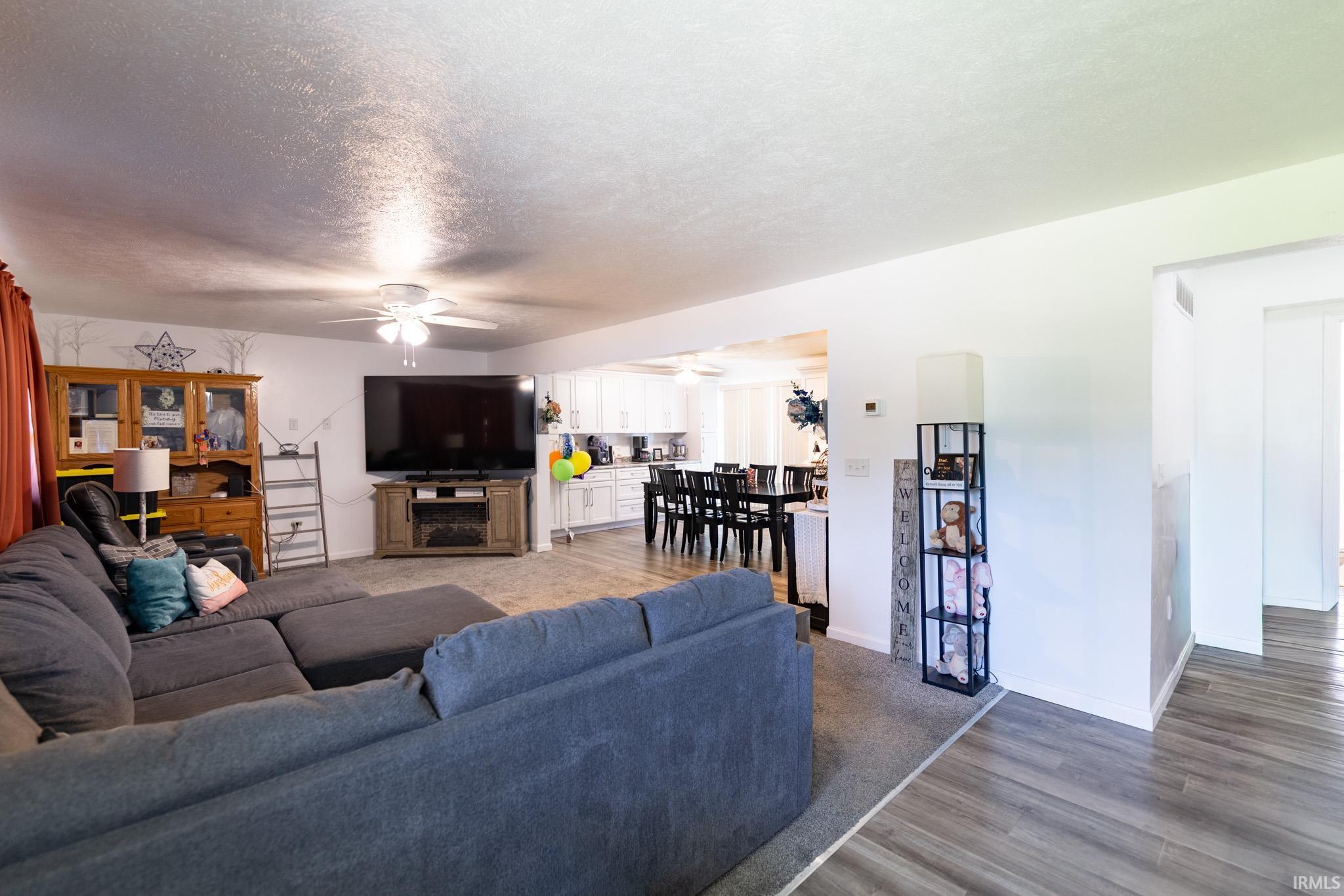Spacious living area featuring neutral carpeting and a ceiling fan