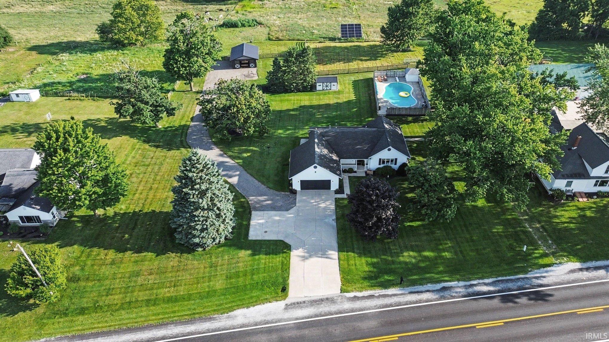 Expansive property featuring a single-story residence with an attached garage, a paved driveway, and a fenced swimming pool