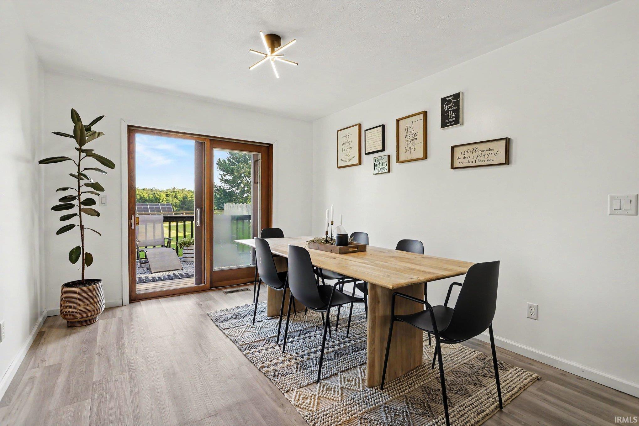 Spacious room featuring wood-finish flooring, white walls, and a contemporary ceiling light fixture