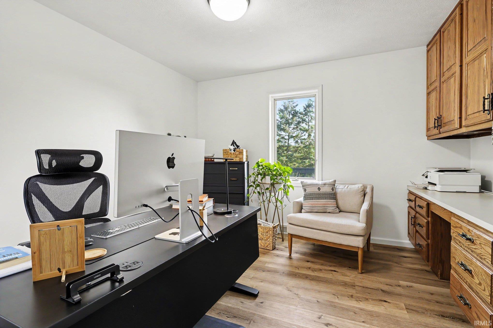 Dedicated office space featuring wood-finish flooring, built-in cabinetry, and a window with exterior views