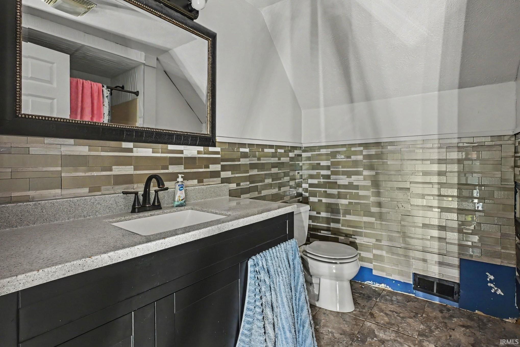 Bathroom featuring a dark wood-finish vanity with a light speckled countertop and integrated sink